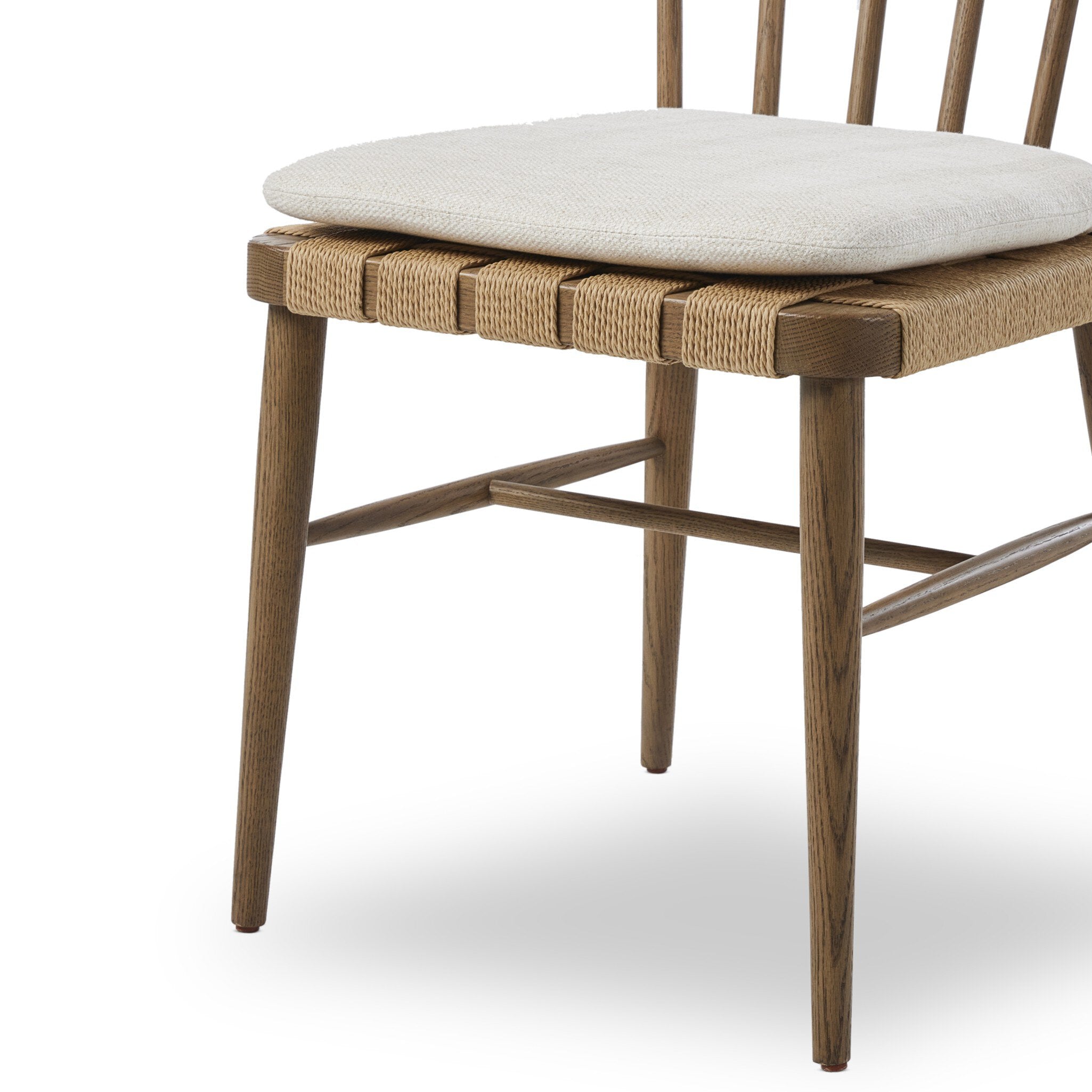 Wooden chair a spindle back, grid-woven seat, and a white cushion on a white background.