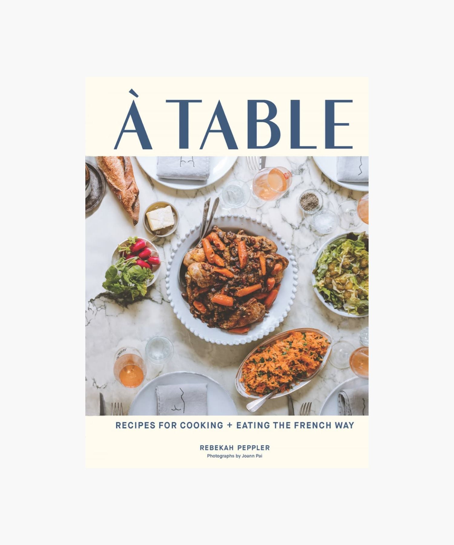 The cover of "À Table" by Rebekah Peppler features a French meal with dishes like roast chicken, carrots, salad, red wine, and bread on a marble table. | SW Home