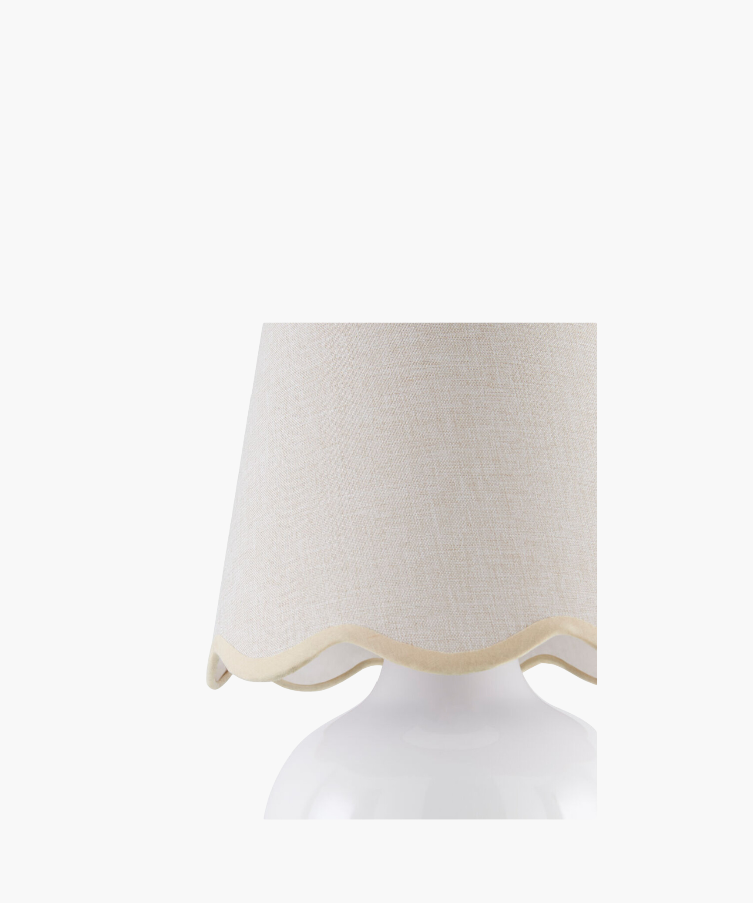 A white ceramic table lamp with a rounded base and a wavy-edged, light beige fabric shade. The design is simple, elegant, and modern.