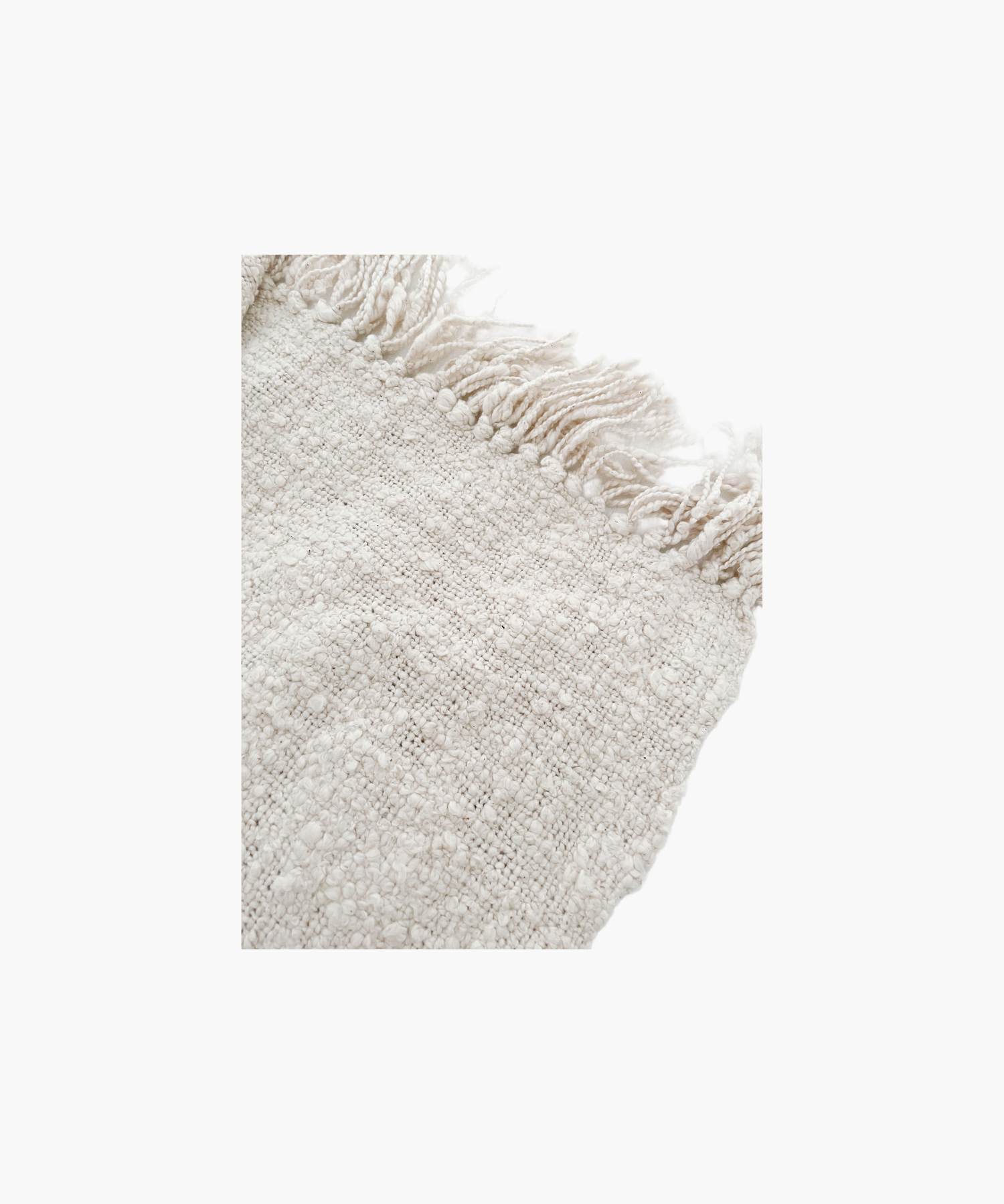 A soft, ivory colored woven throw blanket with a textured pattern and fringed edges, conveying a cozy and inviting feel.