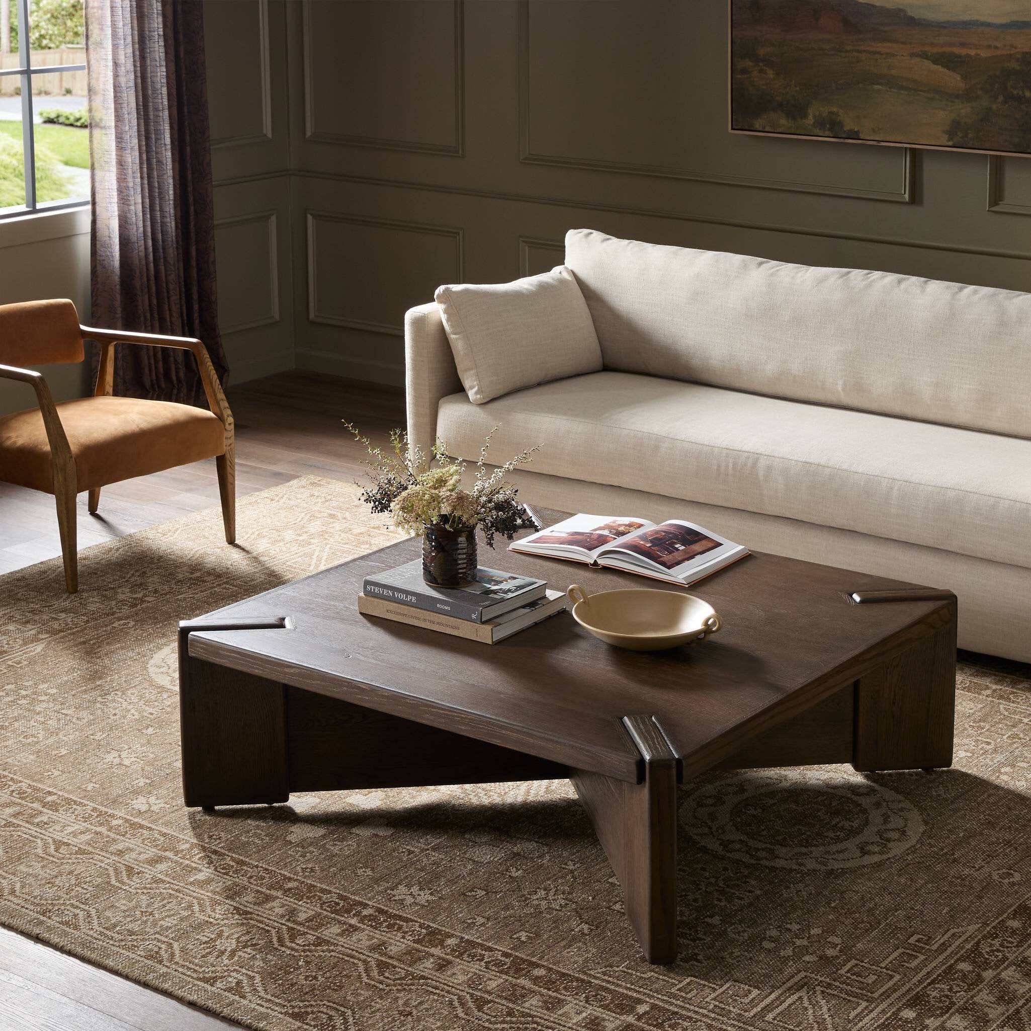 Living room with a beige sofa, brown armchair, and wooden coffee table.