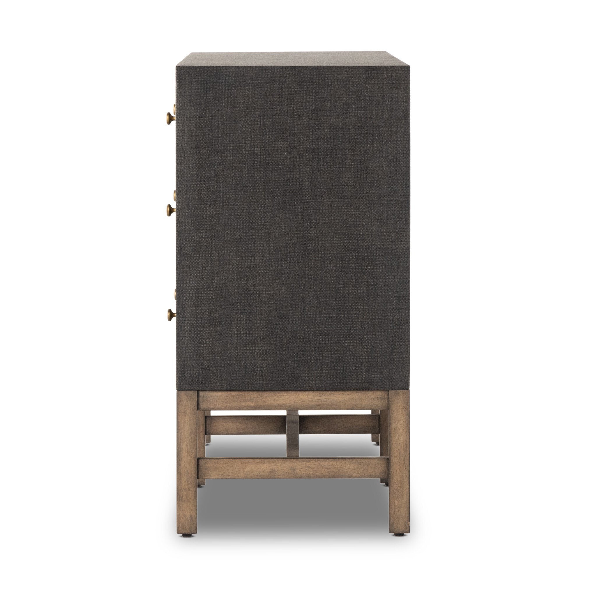 Side profile of a black dresser with brass knobs with wooden legs on a white background.