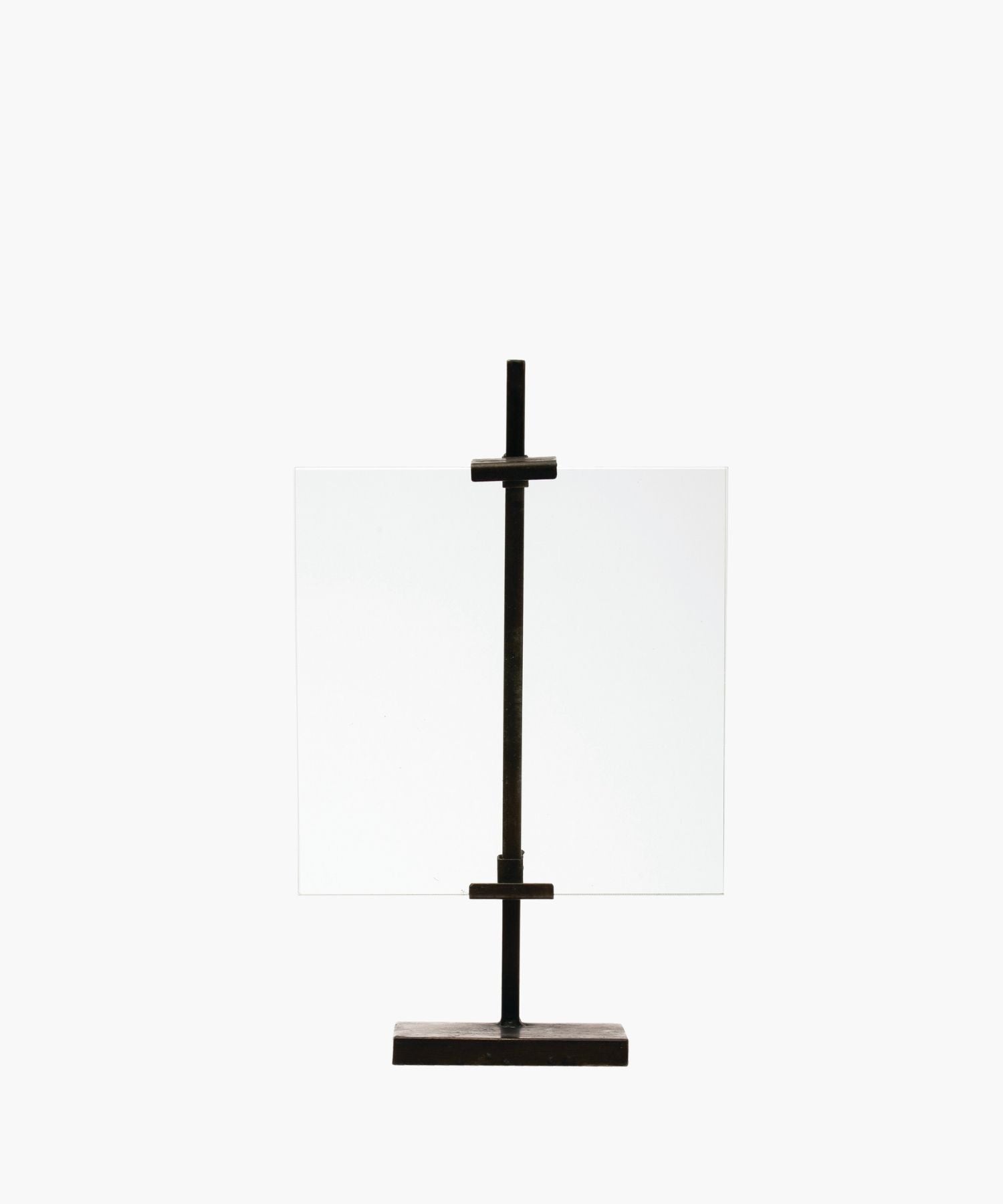A minimalist black metal display stand with a vertical metal clamps holds a clear, rectangular glass sheet. The simple design exudes an industrial, modern feel. | SW Home