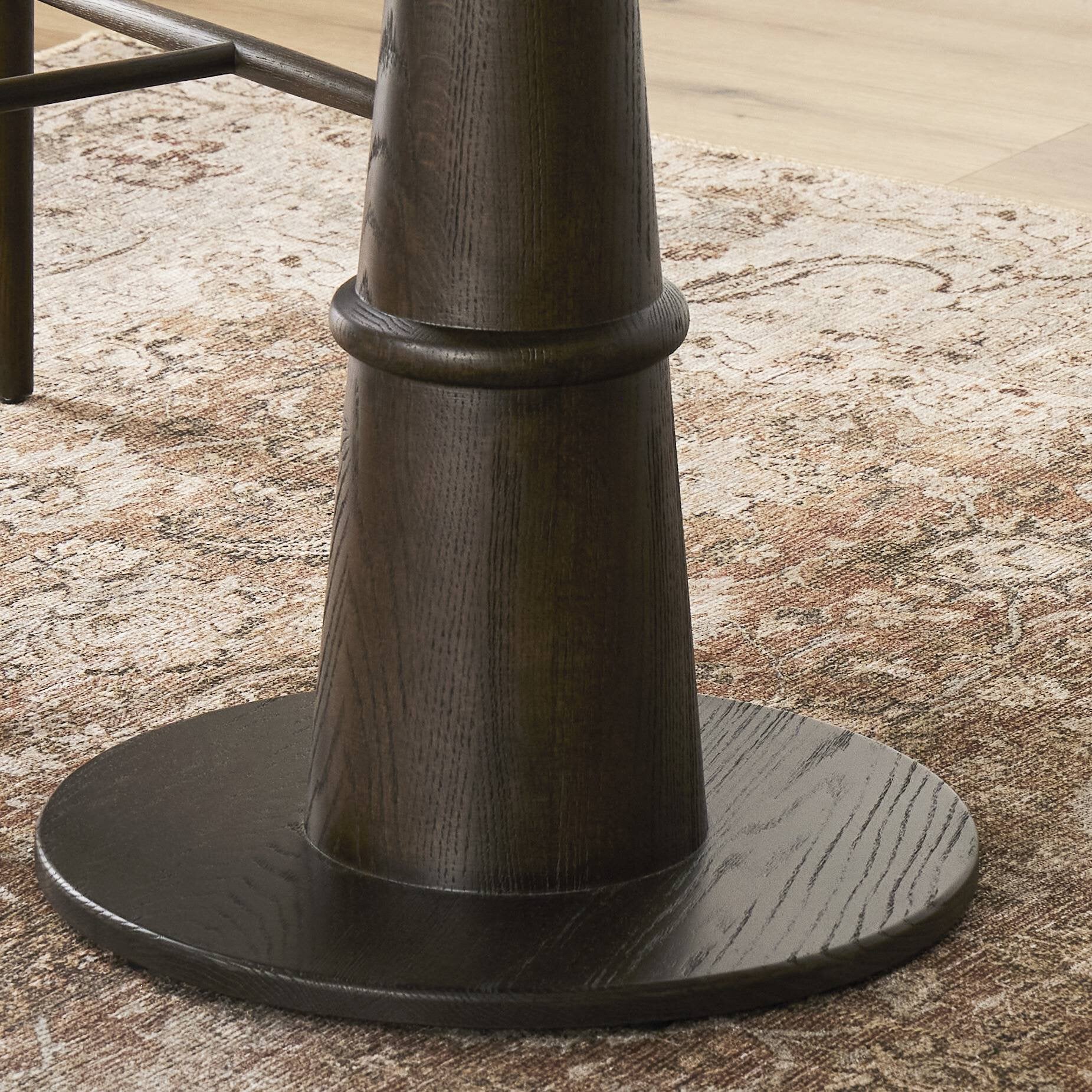 Close up of a round wooden bistro table with a dark brown base on a white background.