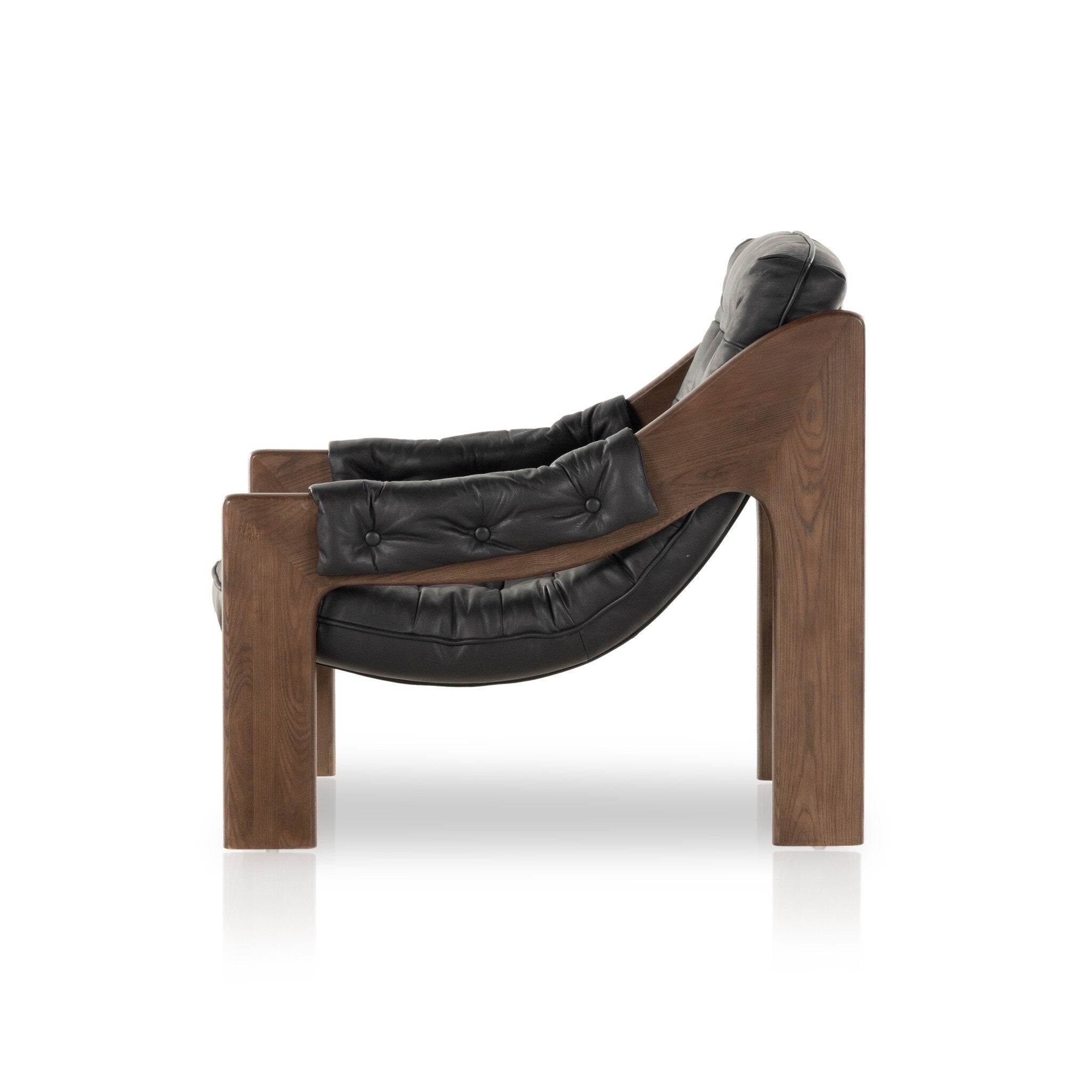 Side profile of a tufted black leather sling style armchair with wooden frame on a white background.