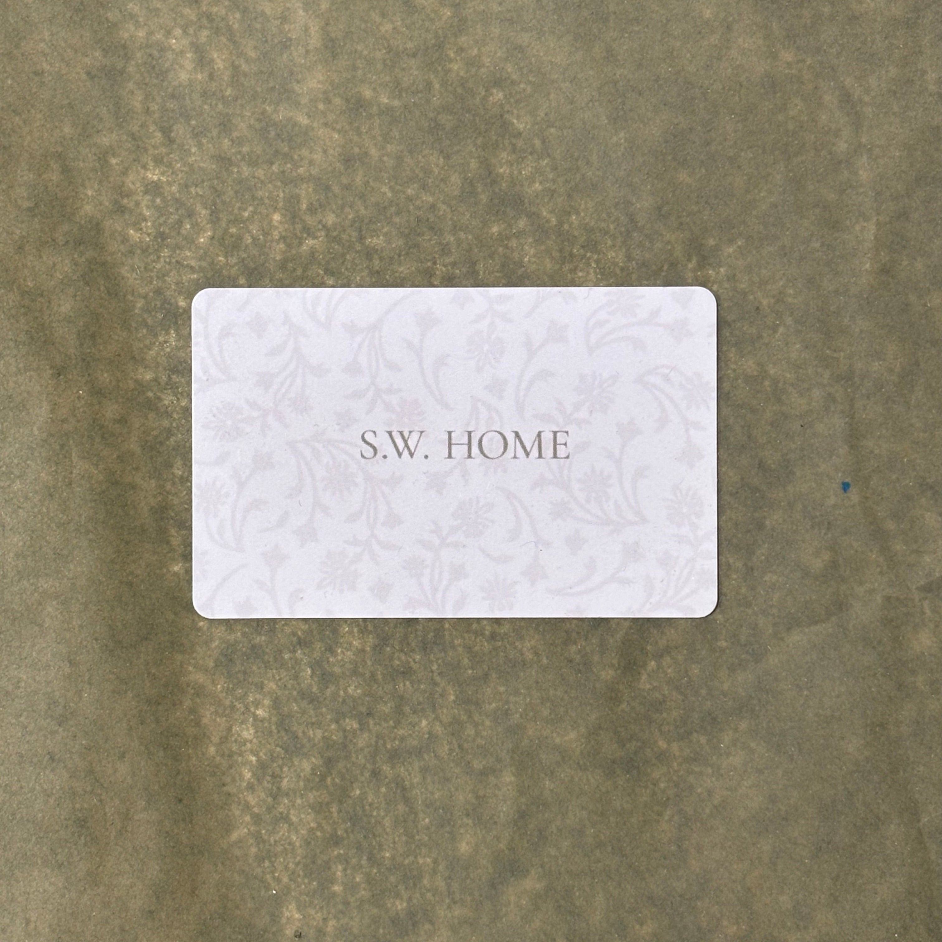 White gift card with 'S.W. HOME' text on a textured sage background