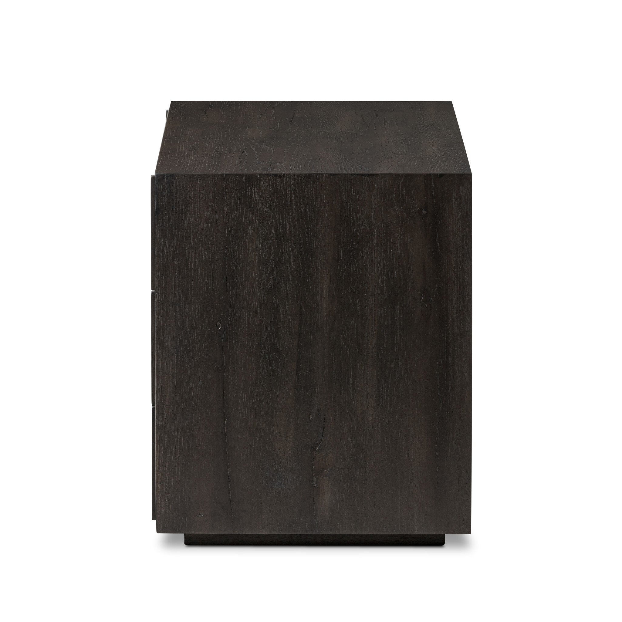 Side profile of a dark wooden dresser with vertical reed detailing and three drawers on a white background.