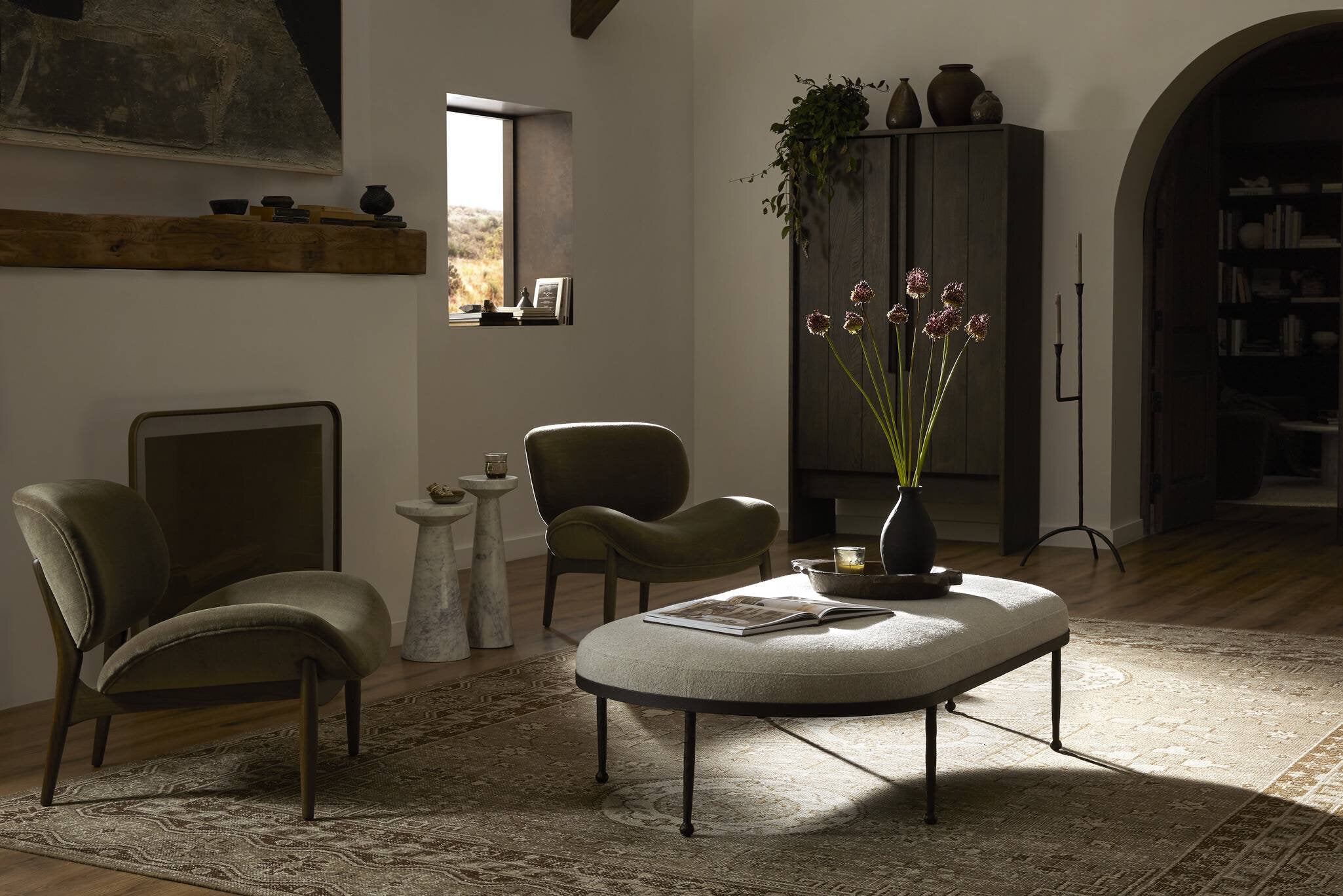 Modern living room with gray chairs, a round ottoman, and decorative elements.