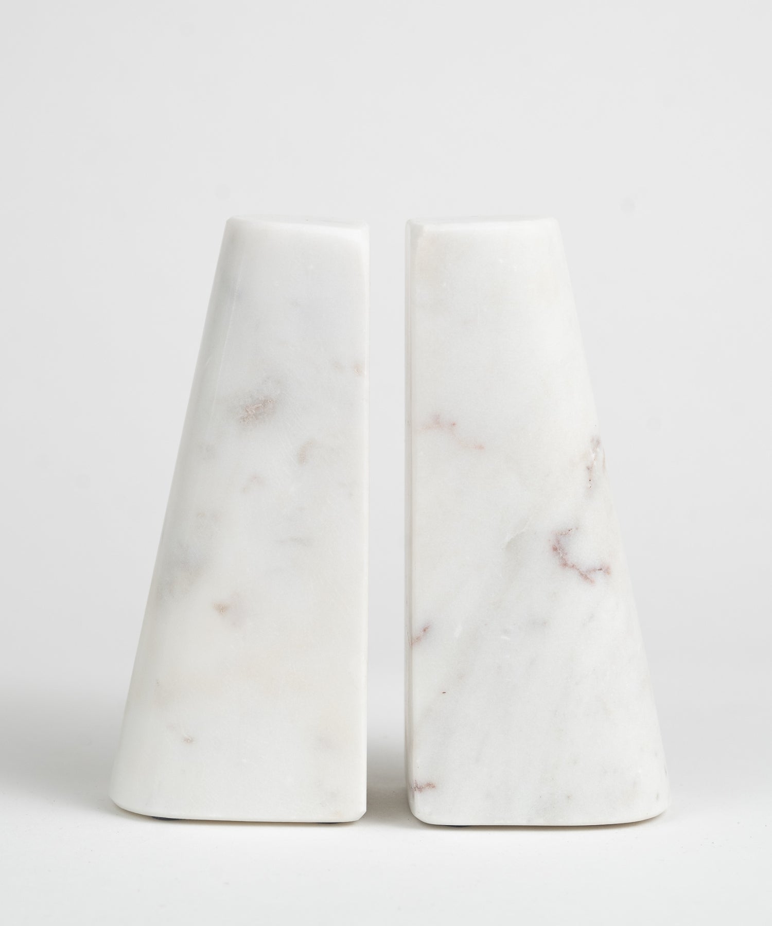 Two white marble bookends with a smooth, conical shape, each featuring subtle brown and gray veining. They appear minimalist and elegant. | SW Home