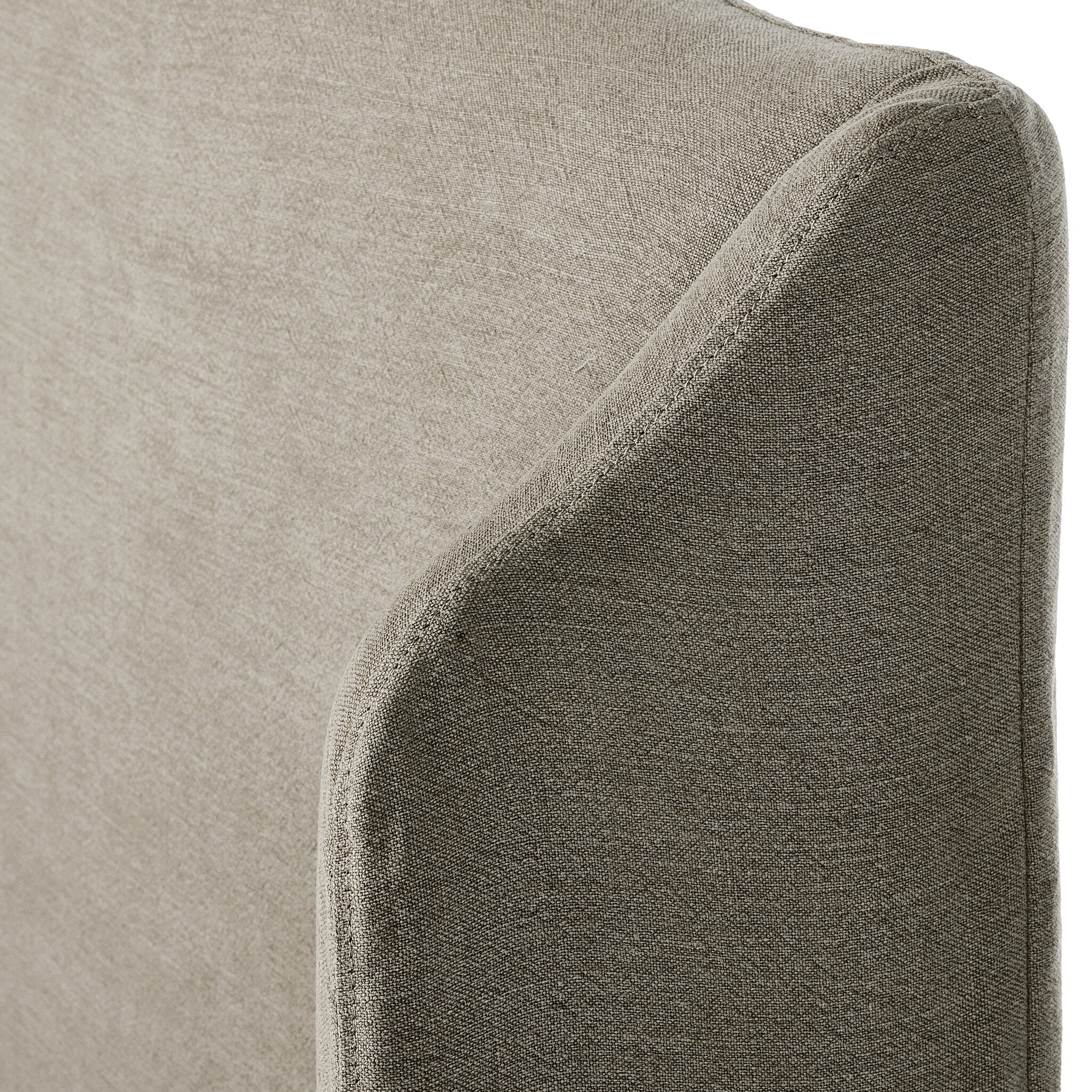 Close up of a beige upholstered bed with white bedding on a white background.