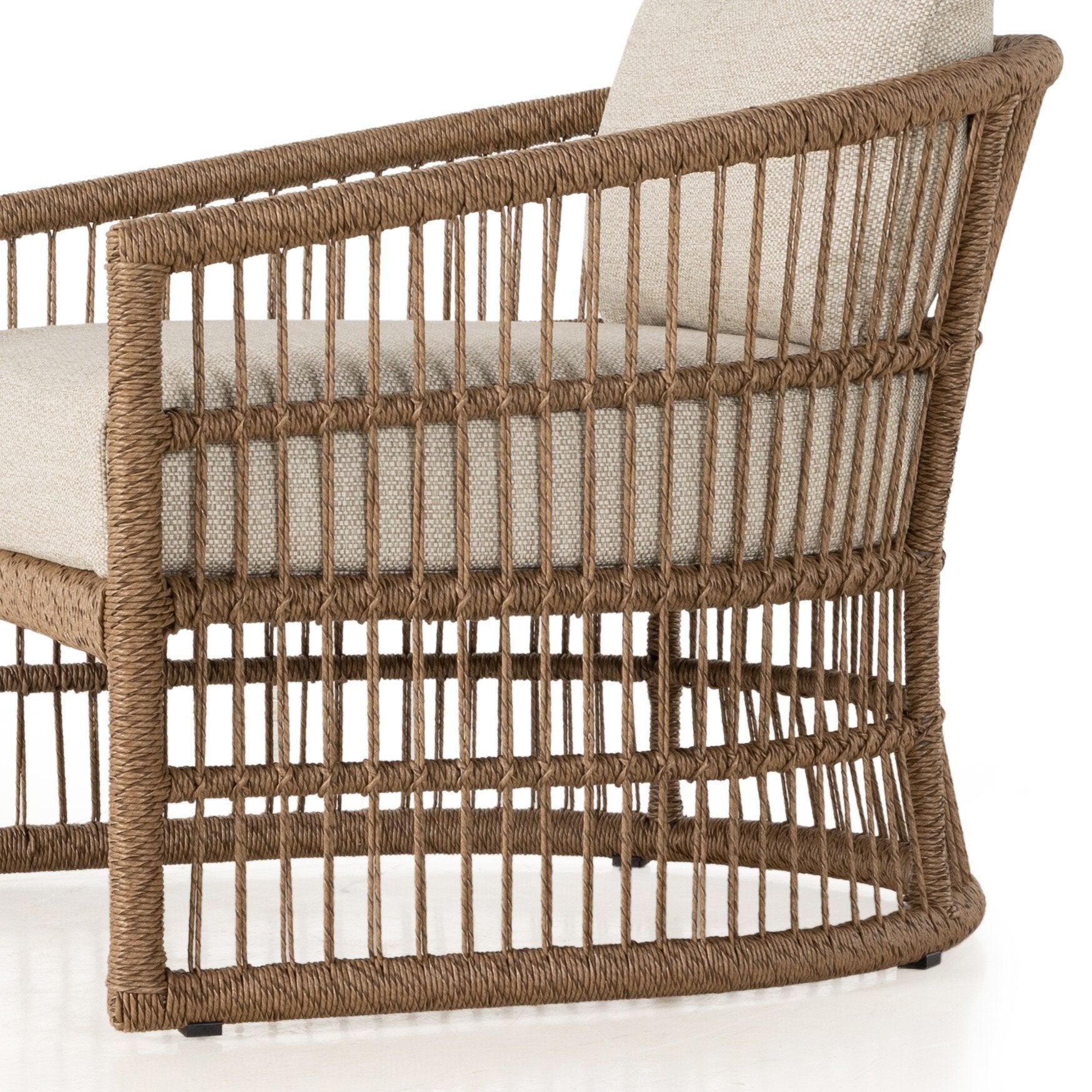 A close up of a cottage inspired outdoor chair with wrapping and texture along with beige colored upholstered cushions on a white background.