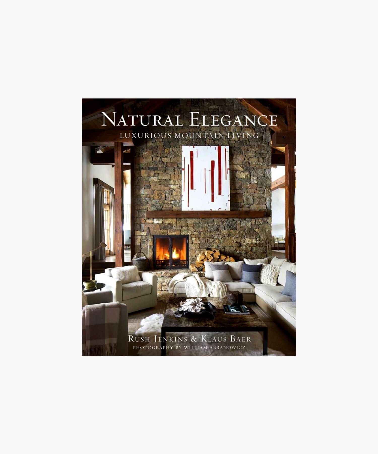 The cover of the book "Natural Elegance: Luxurious Mountain Living" by Rush Jenkins and Klaus Baer features a cozy, elegant living room features a stone fireplace, modern art, and a plush sectional. Warm tones and natural light create a welcoming, luxurious atmosphere. | S.W. Home