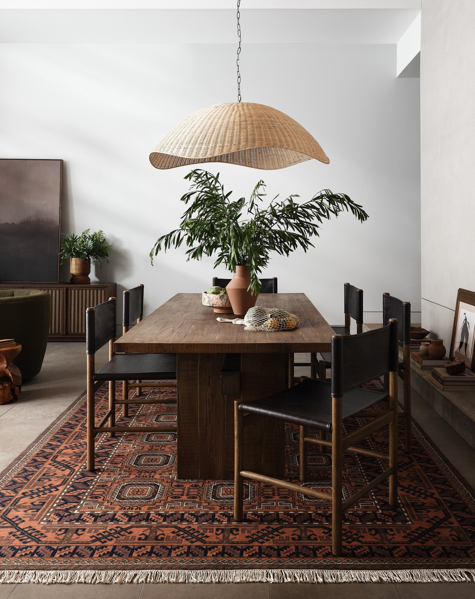 Dining room with wooden table, chairs, and a woven pendant light.