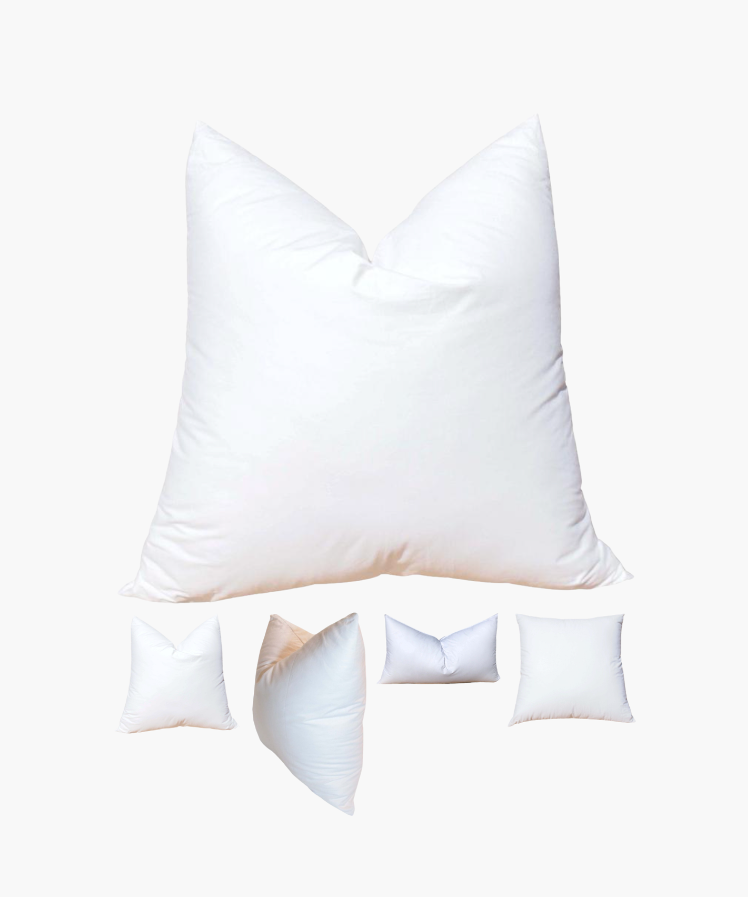 A large white pillow insert centrally displayed, surrounded by four smaller pillow inserts of varying shapes against a plain background, conveying softness and comfort. | S.W. Home