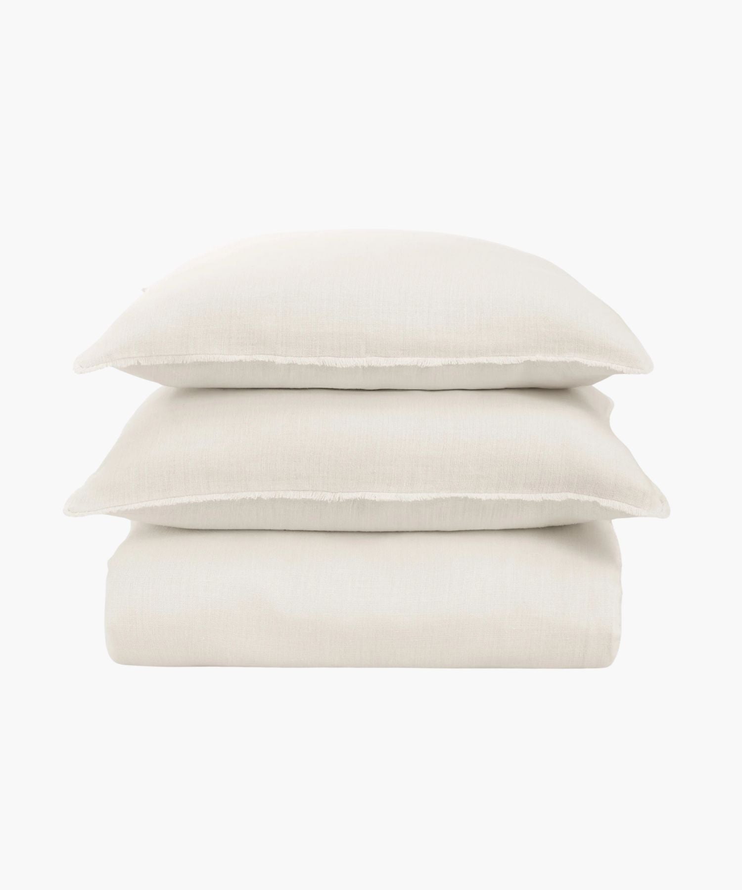 Stack of ivory bedding sheets and pillows on a white background. | Wildwood Home Co.