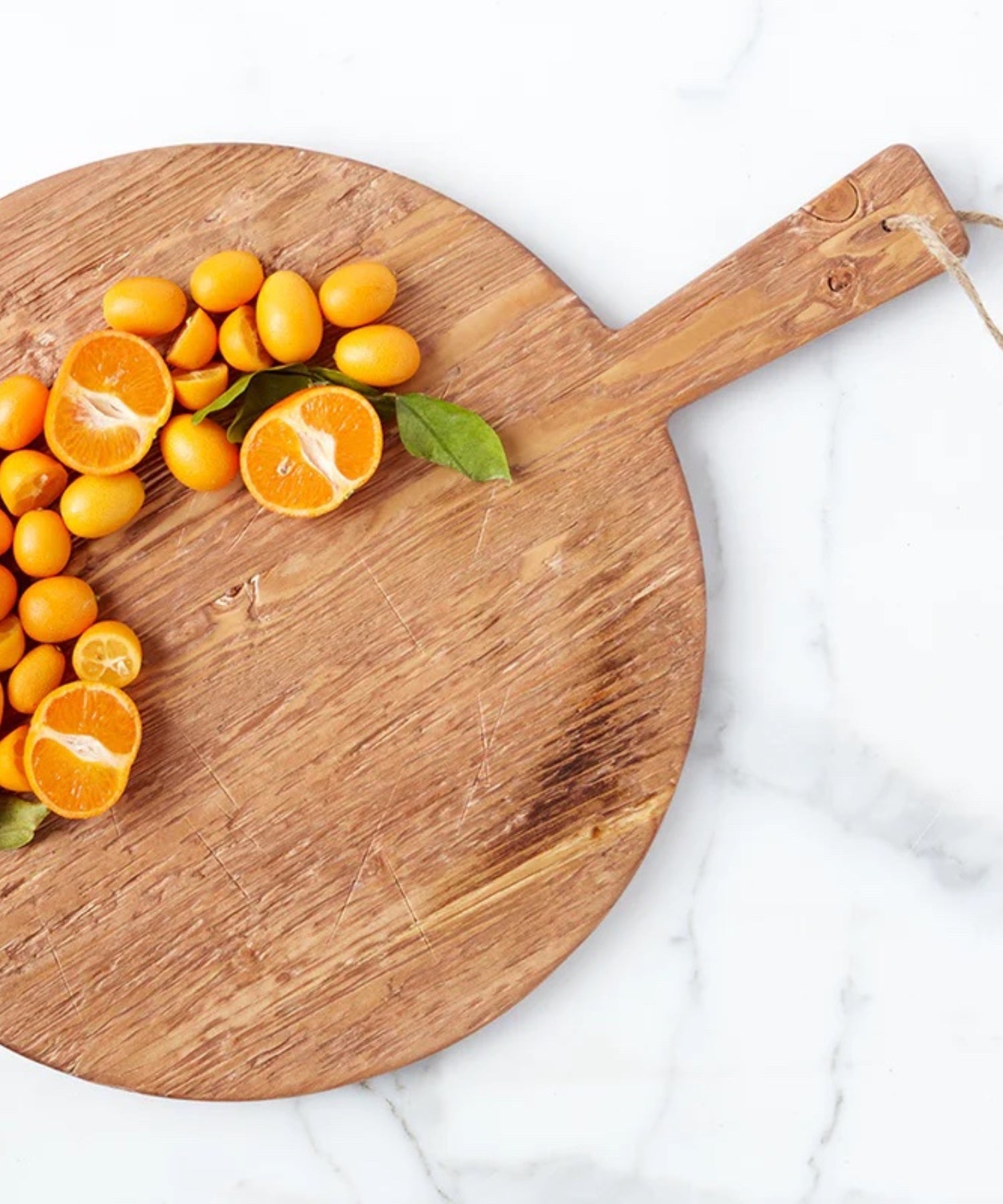 A round pine wood cutting board with a smooth surface and natural grain. It has a handle with a rope loop for hanging, conveying a rustic charm styled with sliced oranges. | SW Home