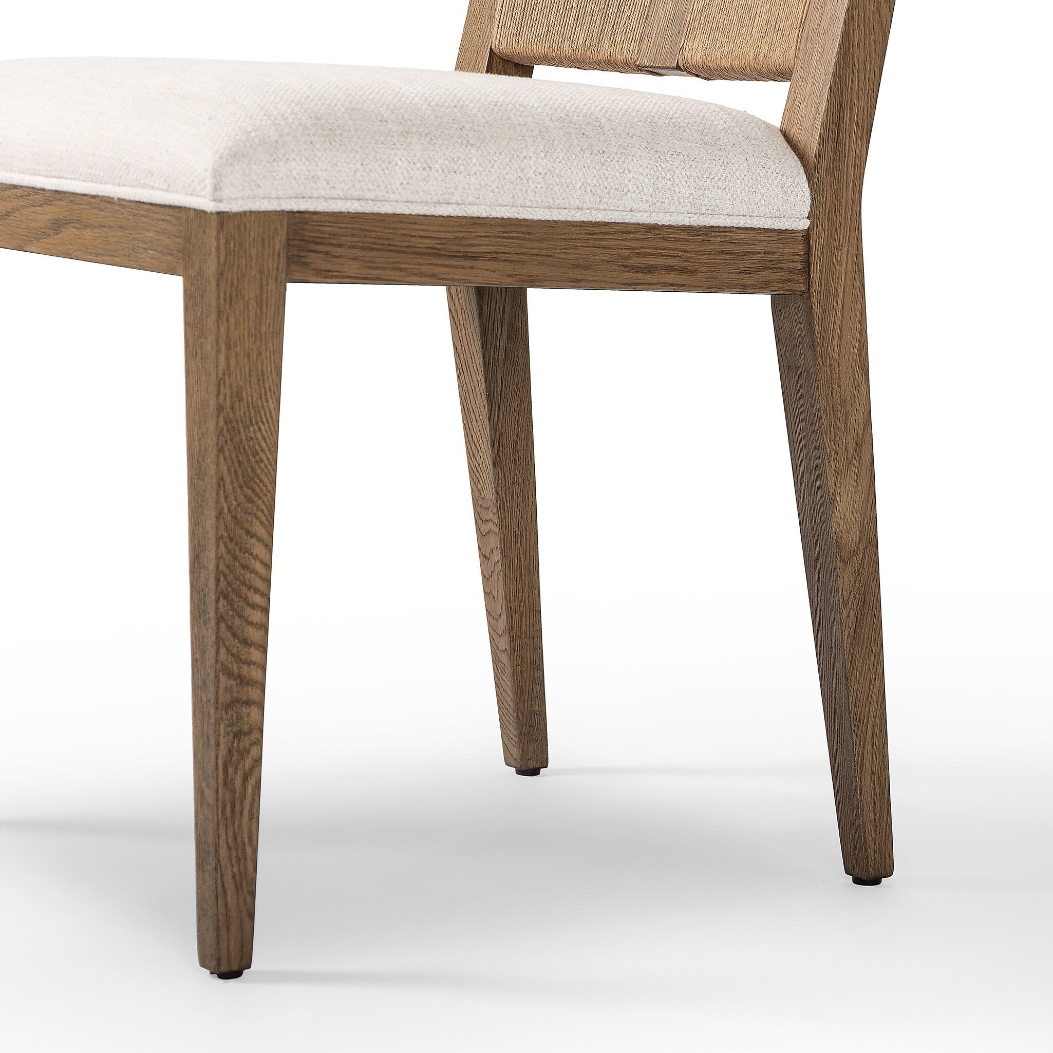 Close up of a wooden dining chair with a woven backrest and white cushion on a white background.