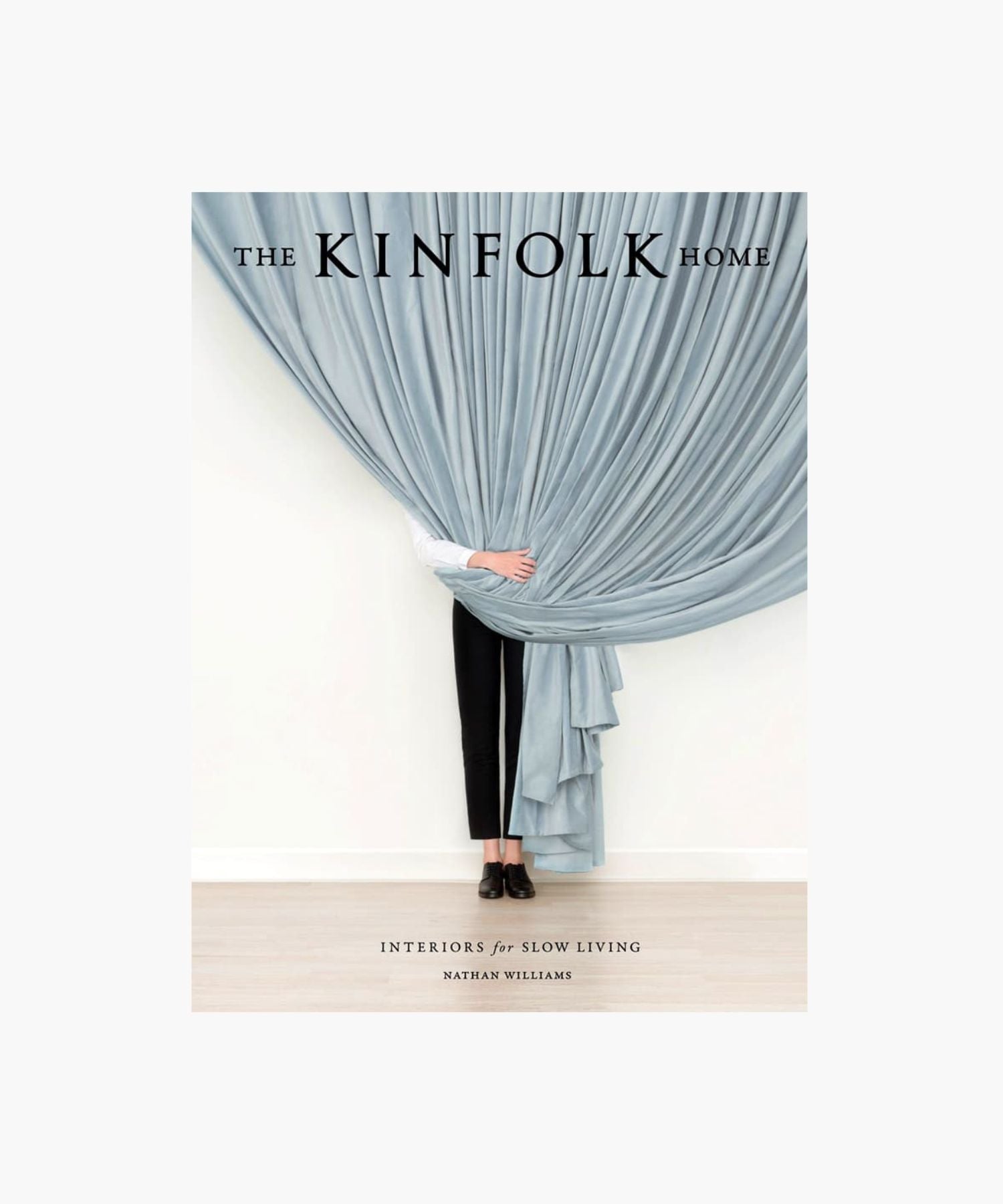 The cover of the book "The Kinfolk Home" by Nathan William features a person partially hidden behind a billowy, light gray curtain. Only their black shoes and lower legs are visible, conveying mystery and minimalism. | S.W. Home