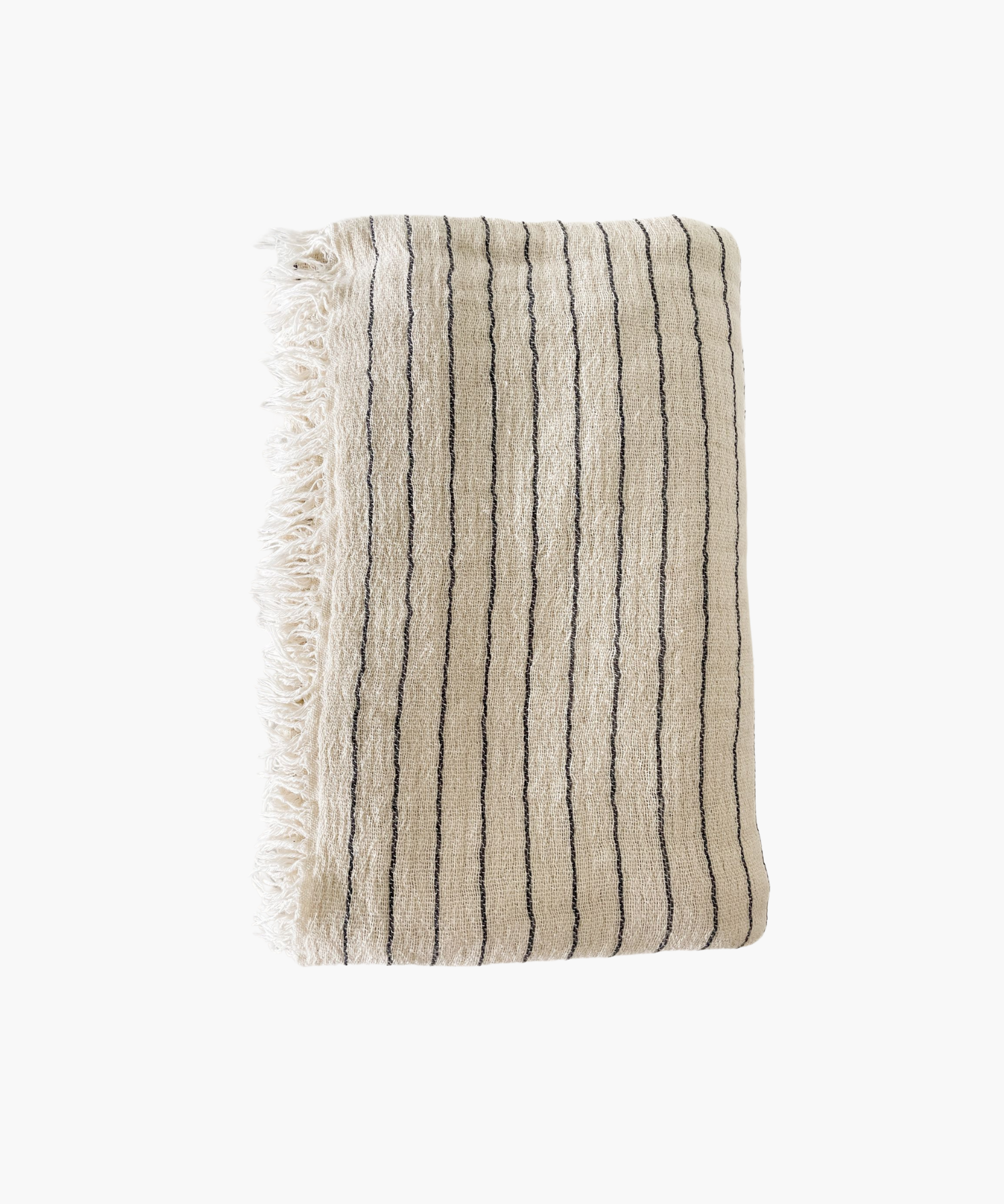A folded beige throw blanket with thin black stripes and fringed edges. The fabric appears textured and soft, evoking a sense of warmth and comfort. | SW Home