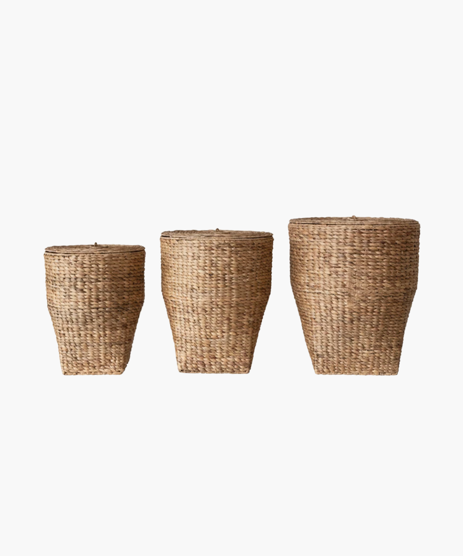 Three woven, conical wicker style baskets of varying sizes with lids are arranged in a row against a white background, displaying natural textures. | Wildwood Home Co.