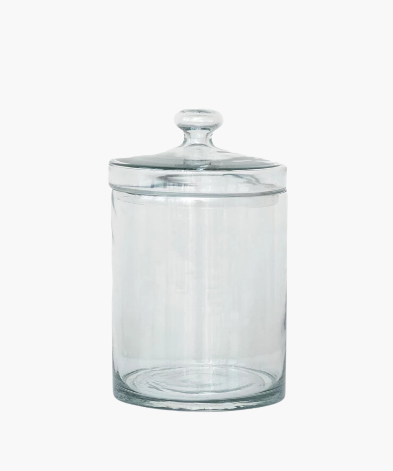 A transparent glass jar with a rounded lid is centered on a white background. The jar is empty and reflects light softly, conveying simplicity and elegance. | S.W. Home