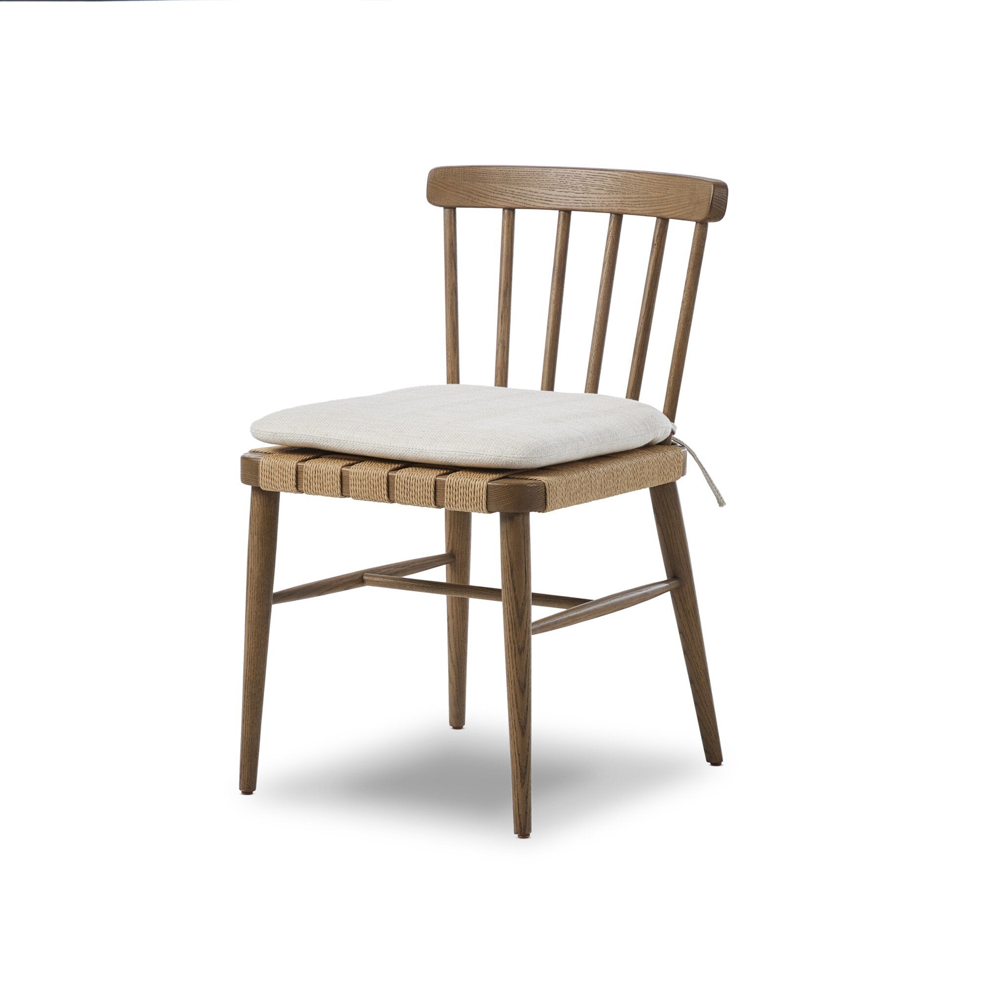Wooden chair a spindle back, grid-woven seat, and a white cushion on a white background.
