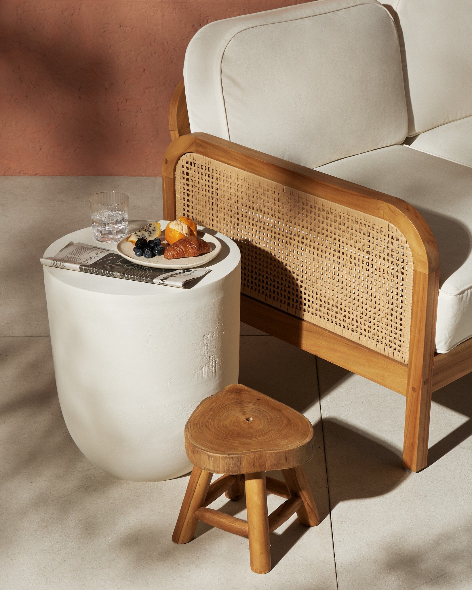 White side table with a plate of food next to a wooden armchair with wicker backrest. | Wildwood Home Co.