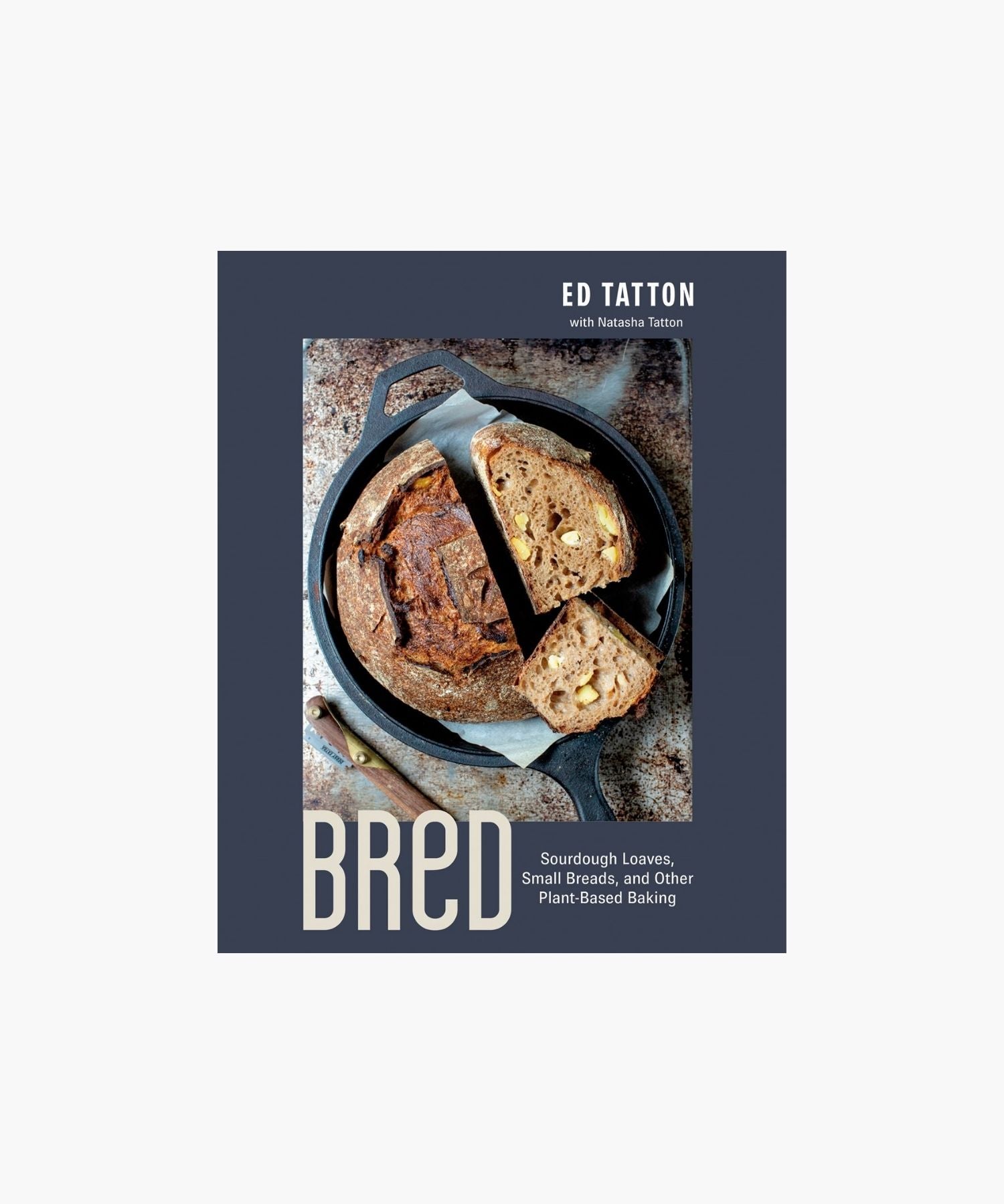 Cookbook cover titled "Bred: Sourdough Loaves, Small Breads, and other Plant-Based Baking" by Ed Tatton features a sliced, rustic loaf in a cast iron pan on a textured surface, conveying a cozy, artisanal feel. | S.W. Home
