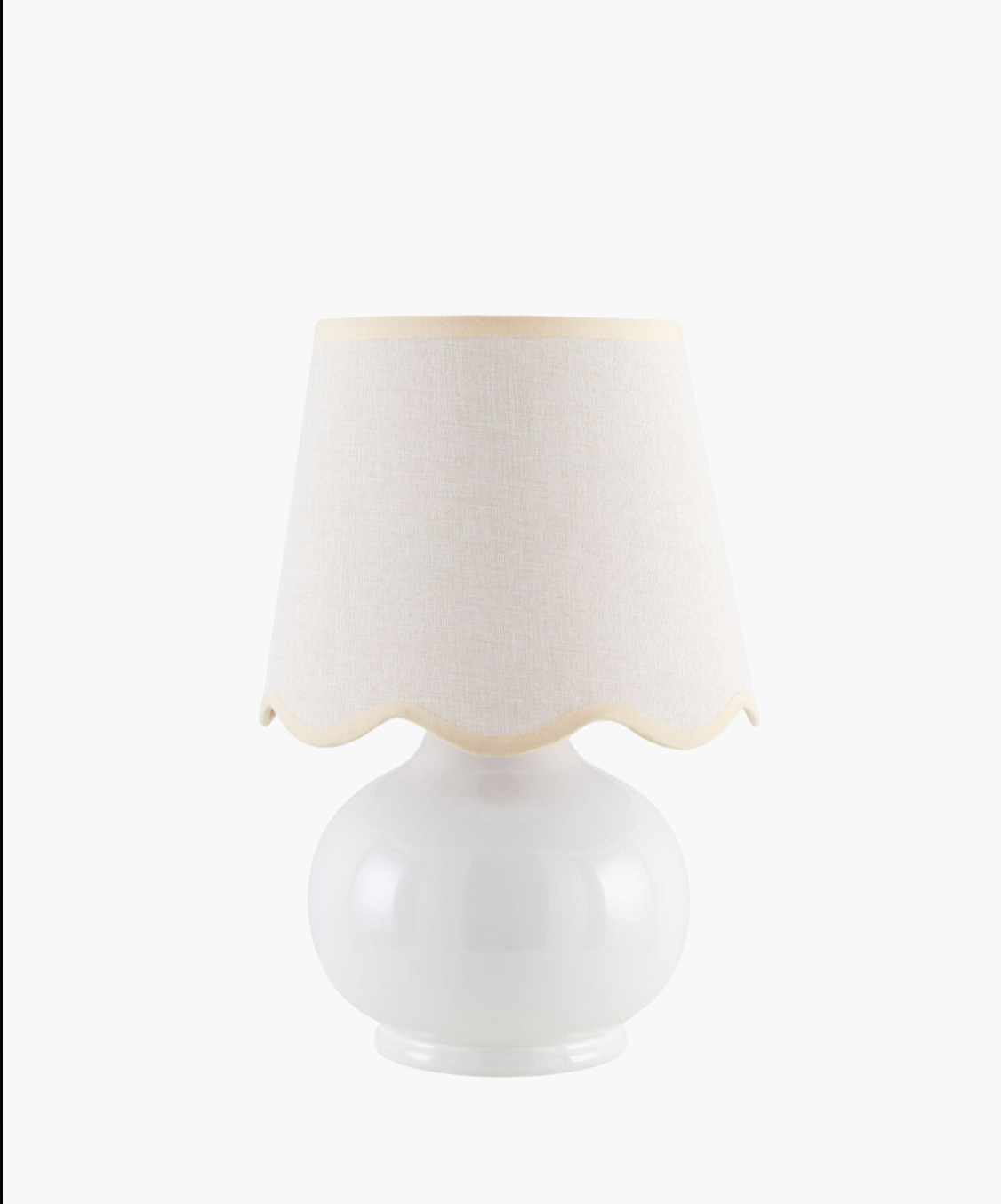 A white ceramic table lamp with a rounded base and a wavy-edged, light beige fabric shade. The design is simple, elegant, and modern.