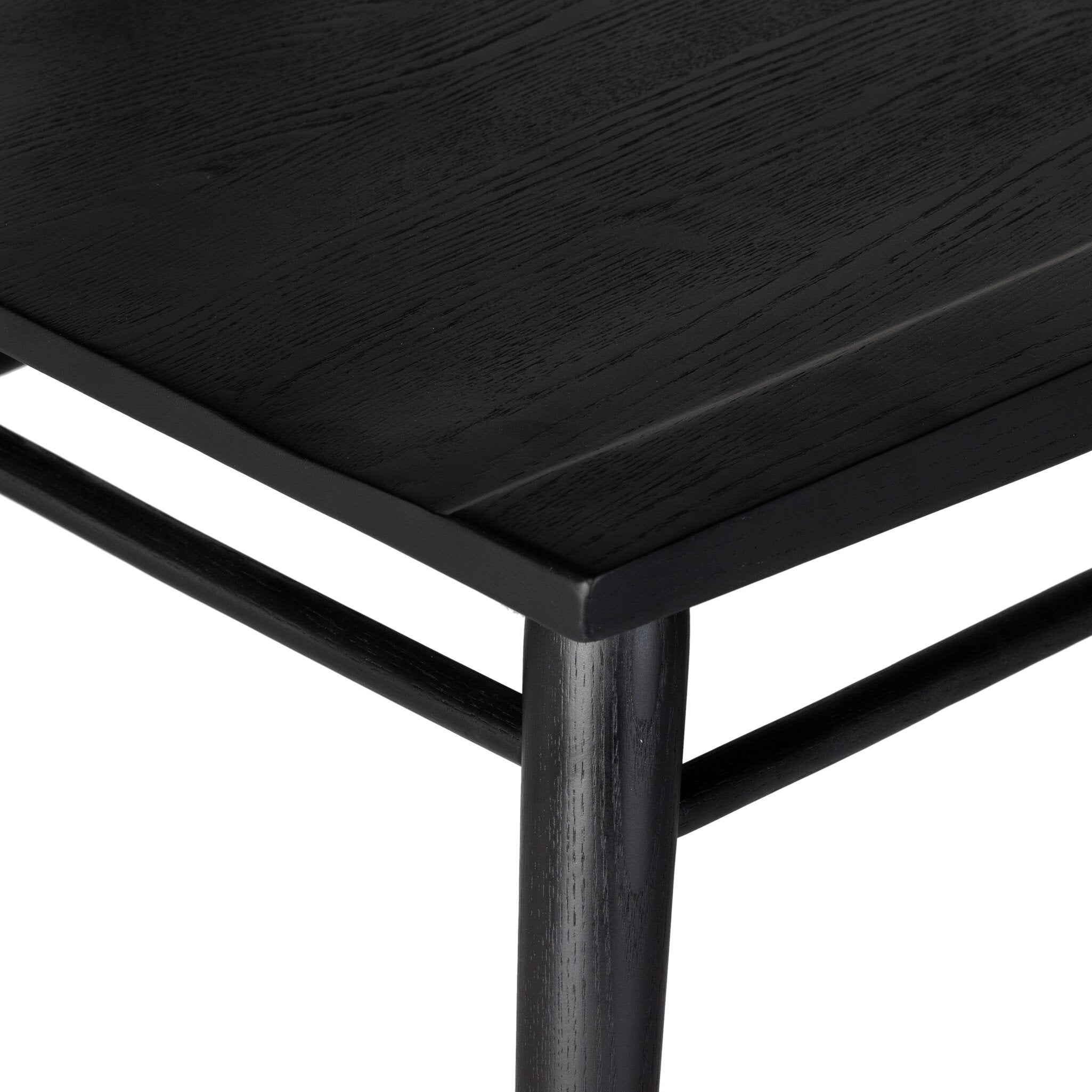 Close up of a black dining chair with a minimalist design on a white background.
