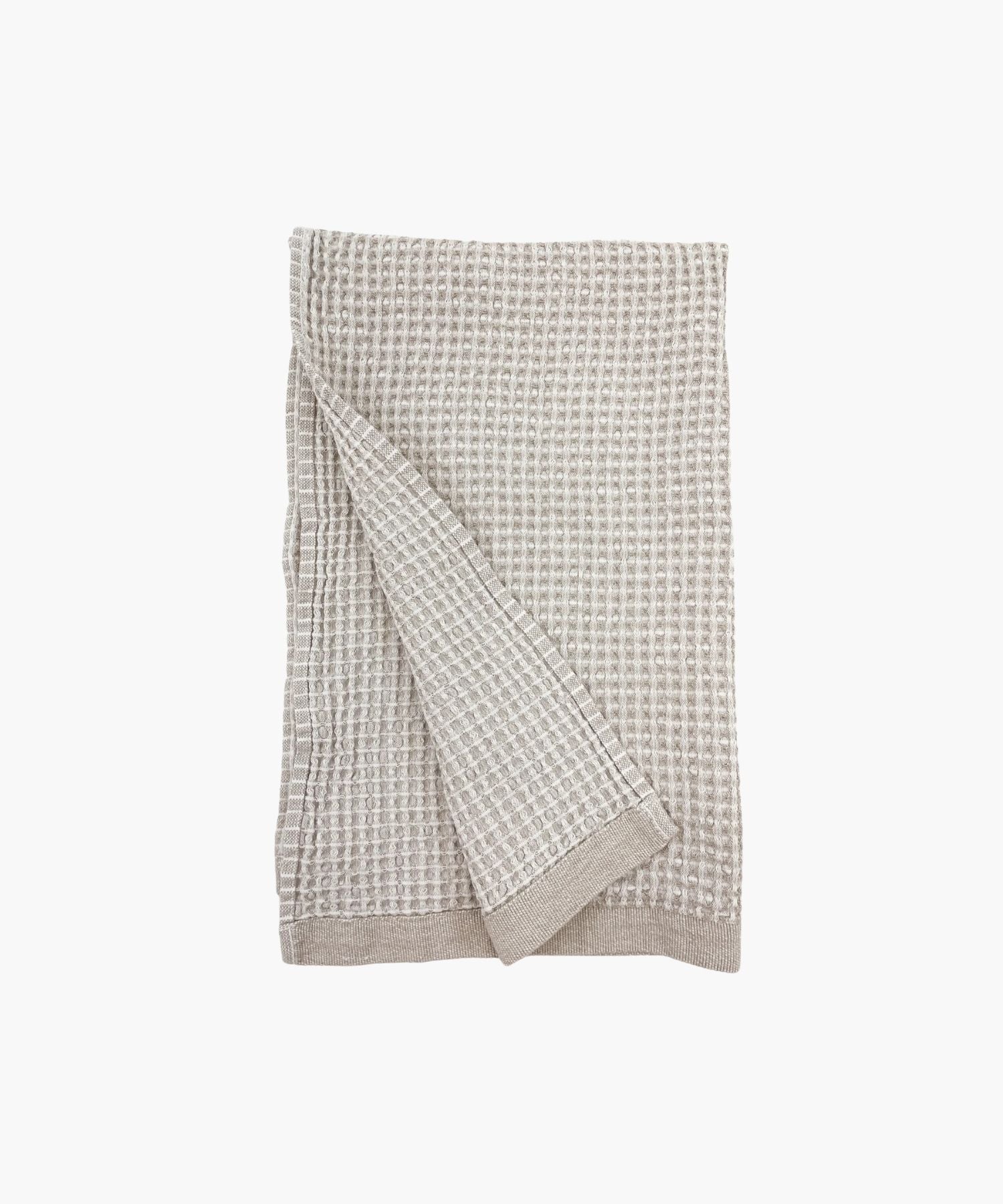A folded beige waffle‑weave towel with a textured pattern, displayed against a white background.  | S.W. Home
