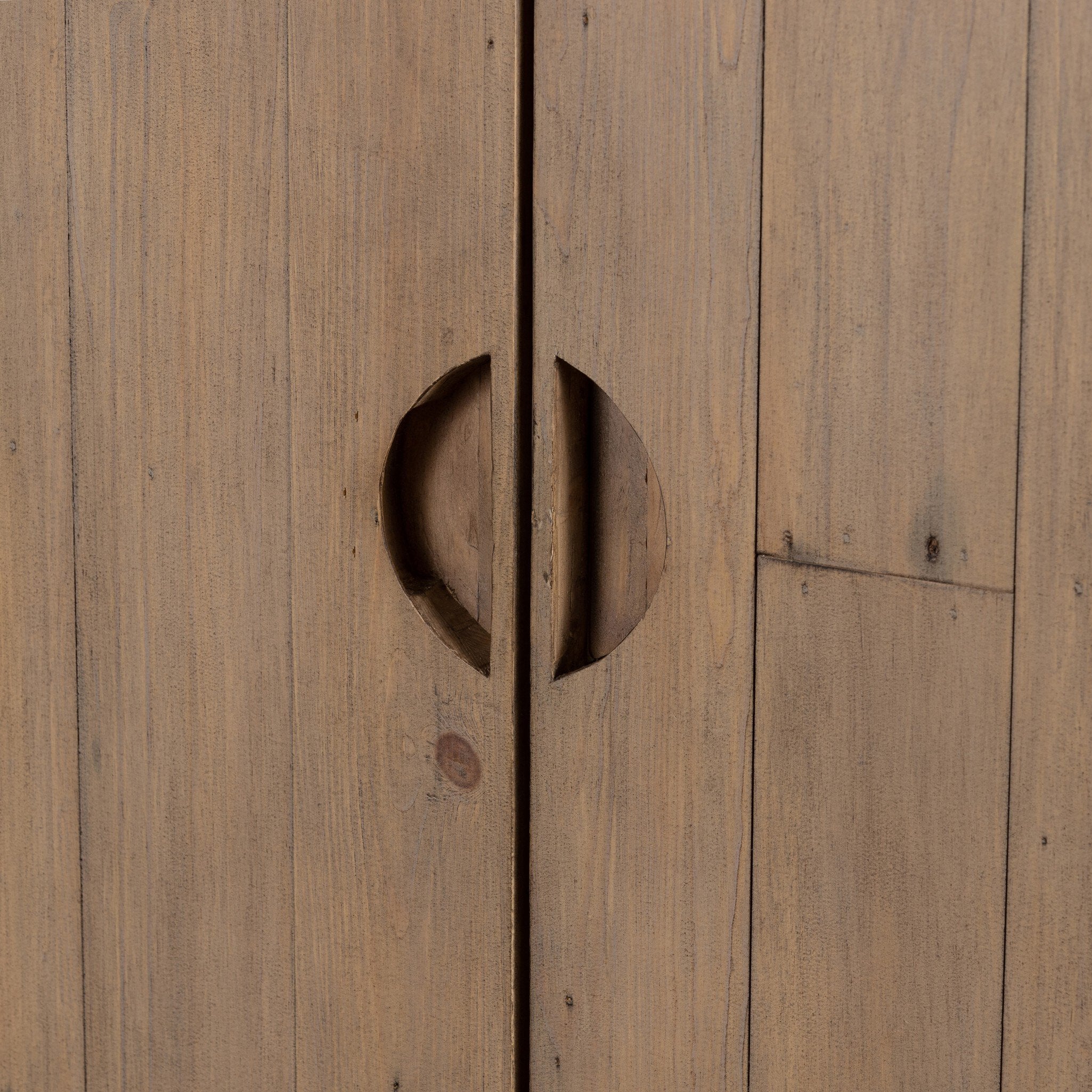 Close up of the handles of a  a wooden cabinet with two doors and rounded corners on a white background.