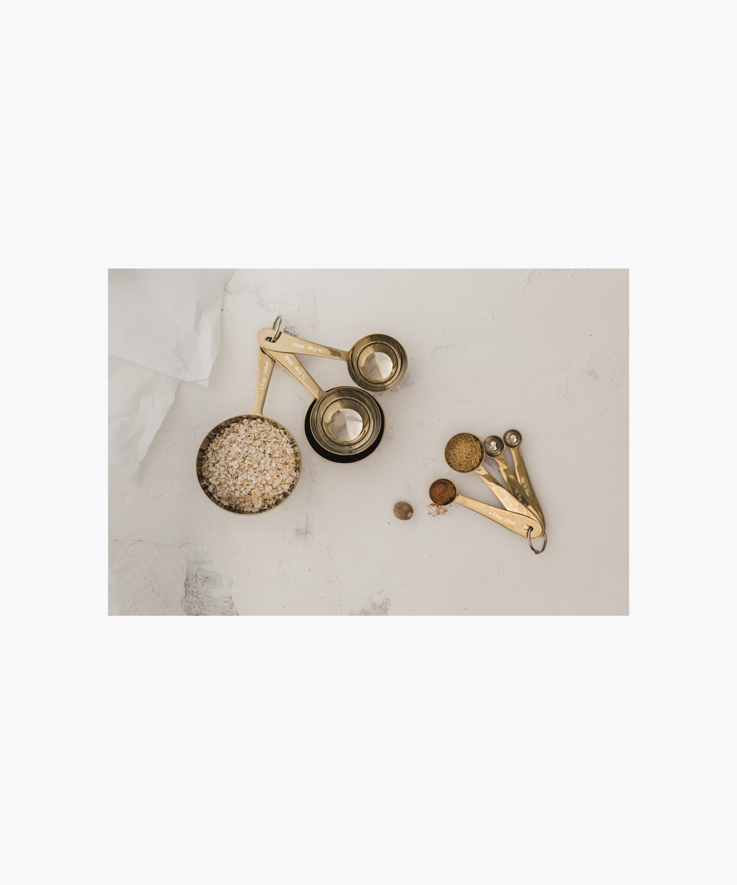 Four nested gold measuring spoons are attached by a metal ring, labeled with measurements styled with matching gold measuring cups.  | Wildwood Home Co.