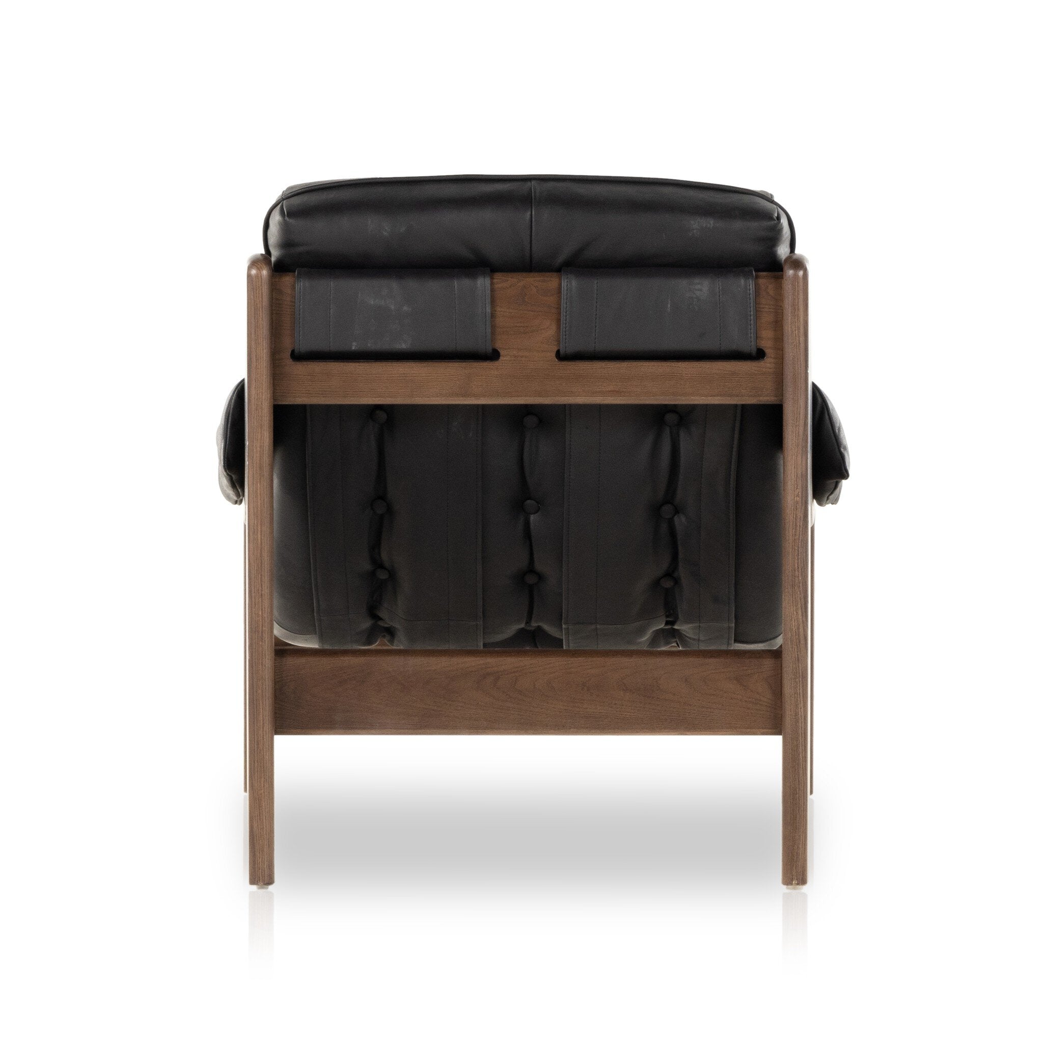 The back of a tufted black leather sling style armchair with wooden frame on a white background.