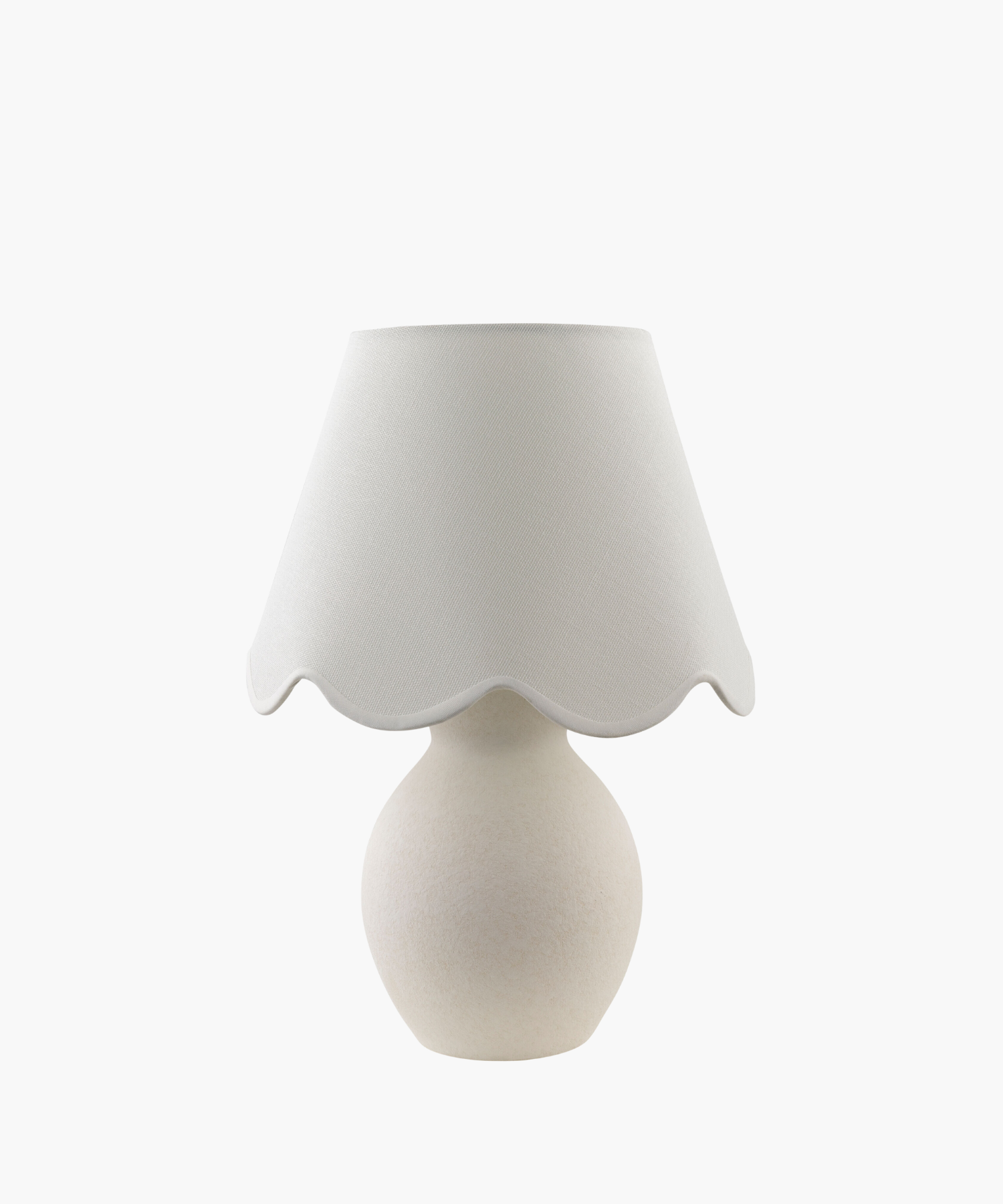 A cream-colored table lamp with a rounded base and a scalloped fabric shade, conveying a cozy and elegant feel. The design is minimalist and classic. | S.W. Home