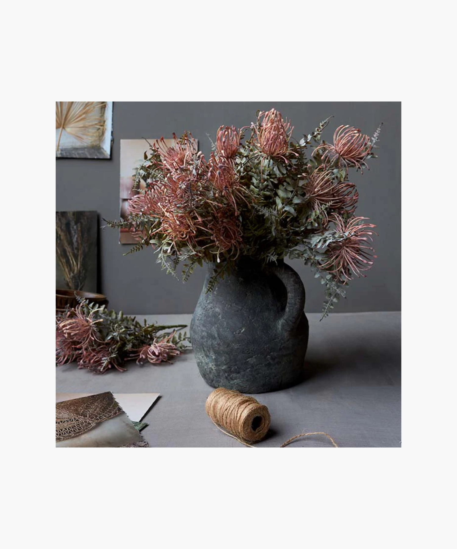 A Leucospermum bush with green and pink leaves in a grey vase , intended for home decor purposes. | SW Home