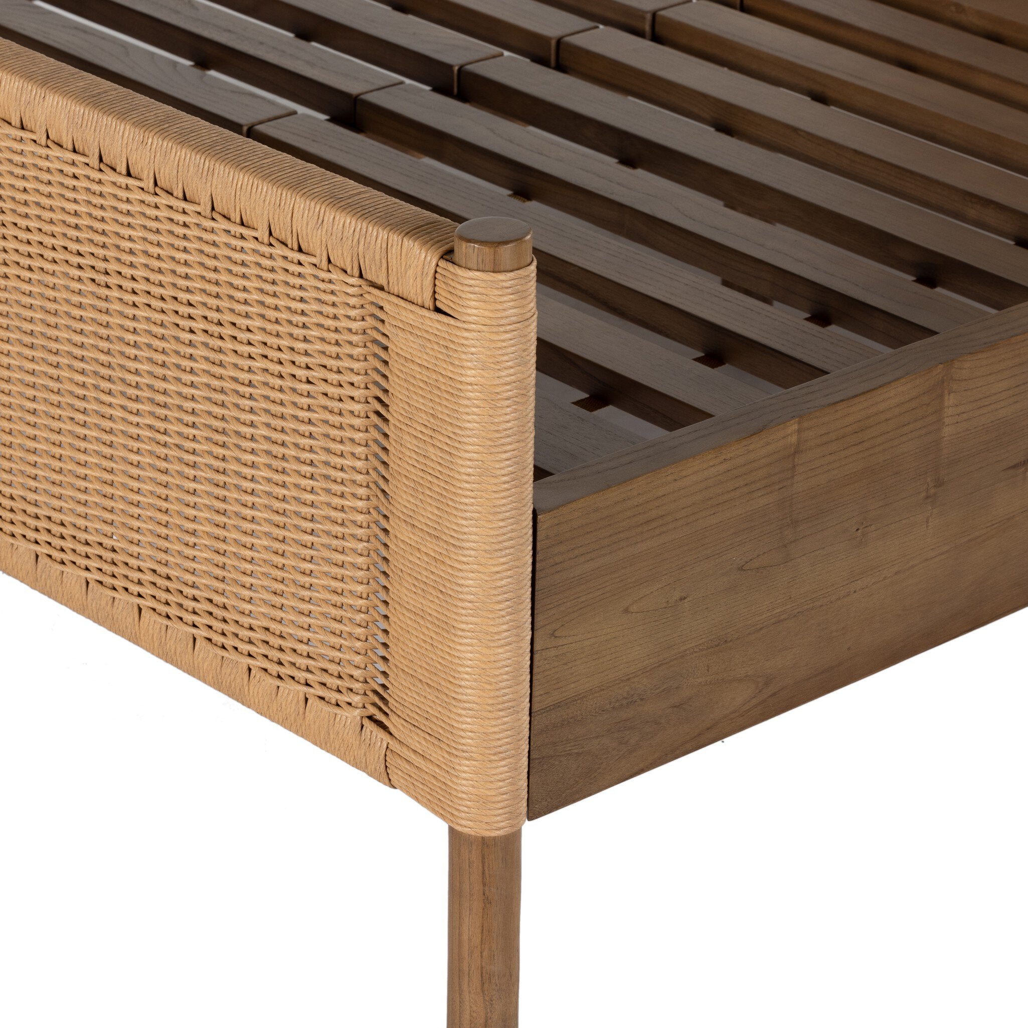Close up of a wicker bed with white bedding on a white background.