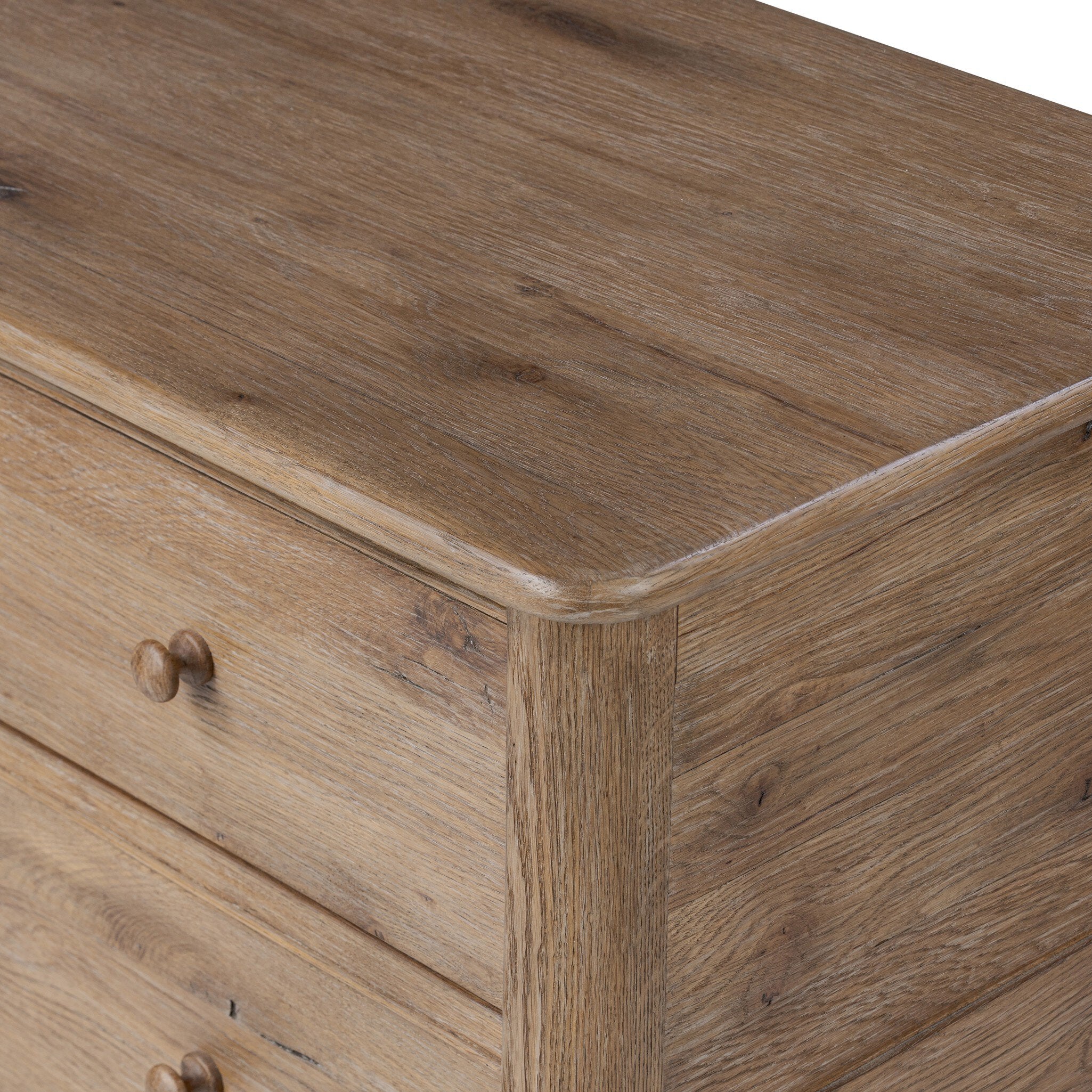 Close up of a wooden dresser with four drawers on a white background.