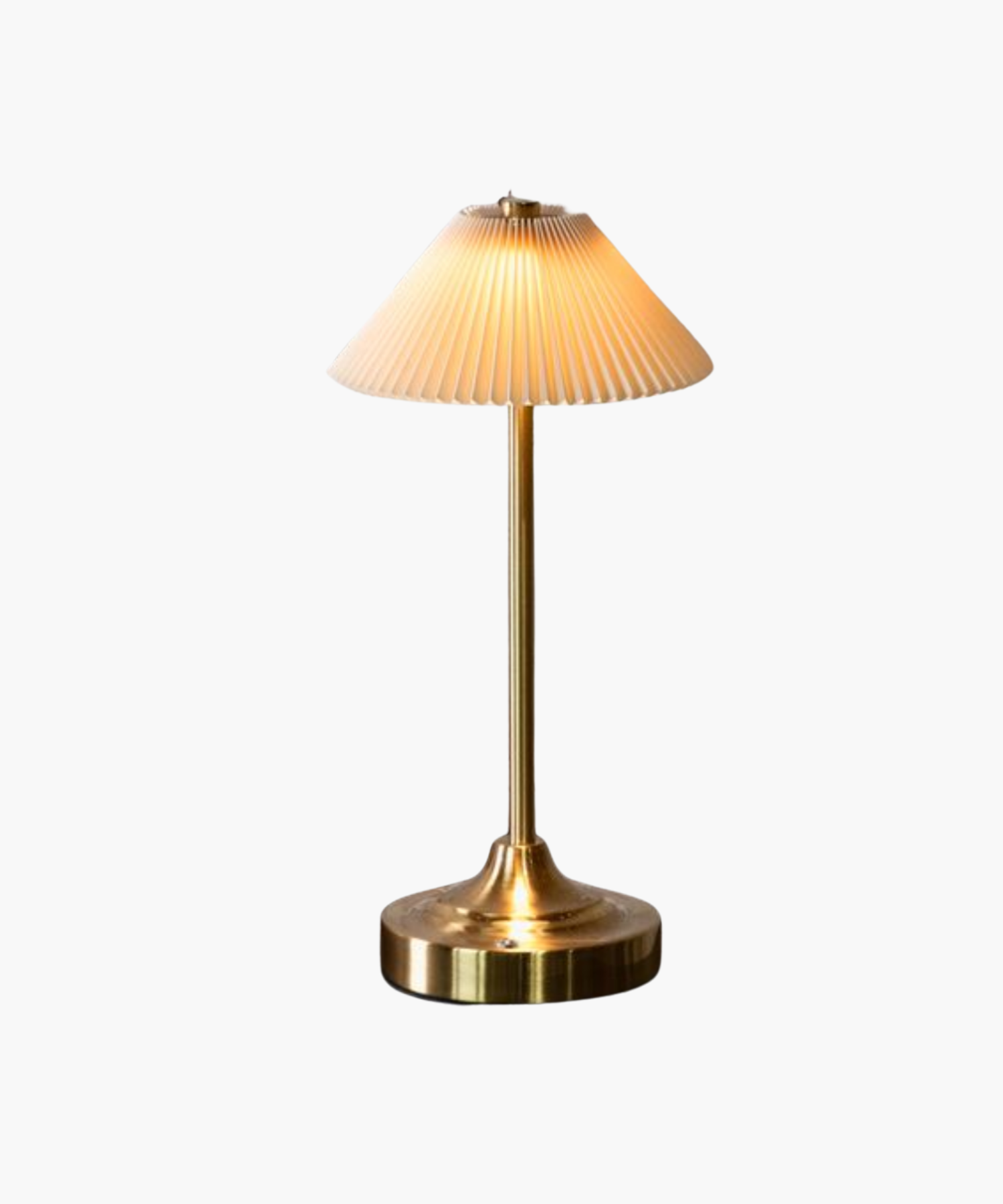 A warm, glowing brass table lamp with a fluted white shade sits on a reflective surface. The sleek design and soft lighting create an elegant and cozy ambiance. | S.W. Home

