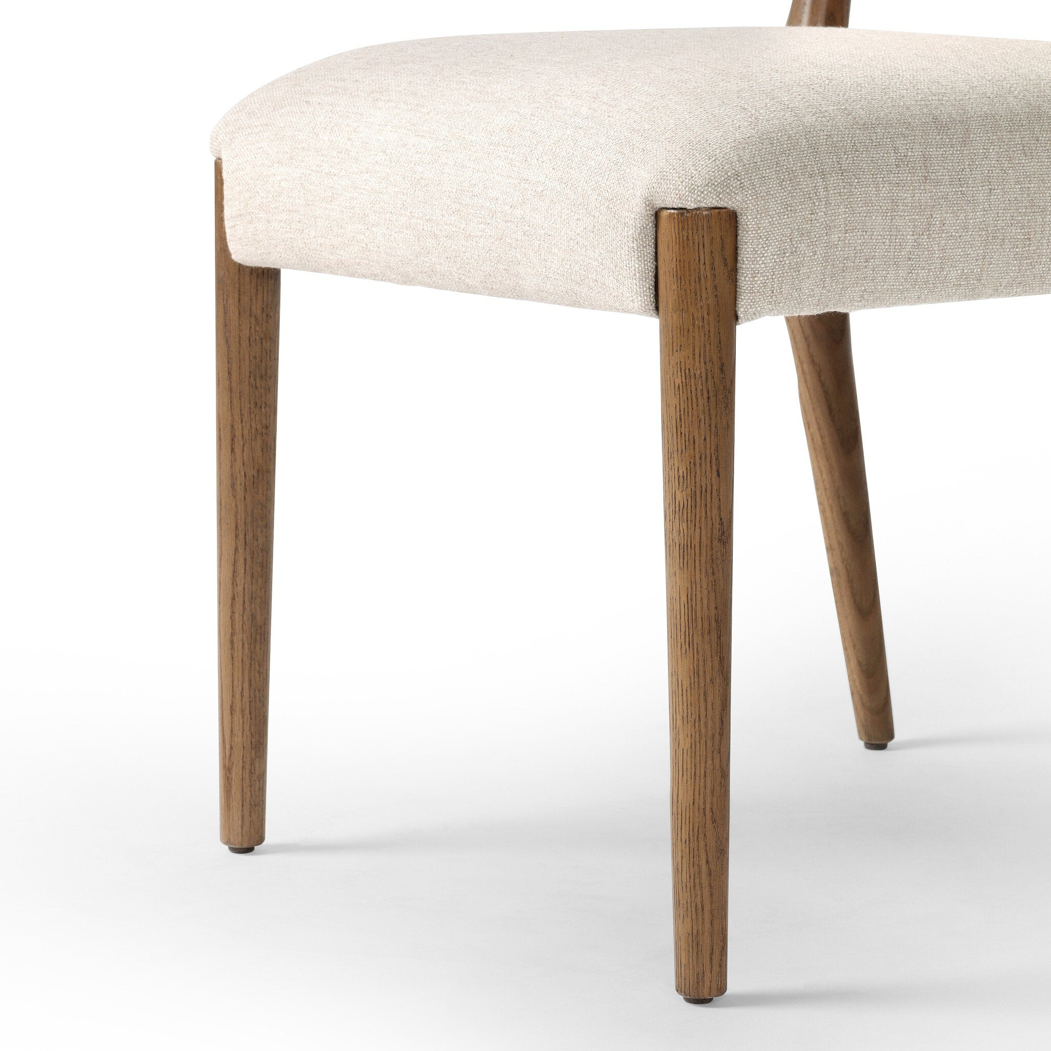 Close up of a dining chair with woven backrest and beige cushion on a white background.