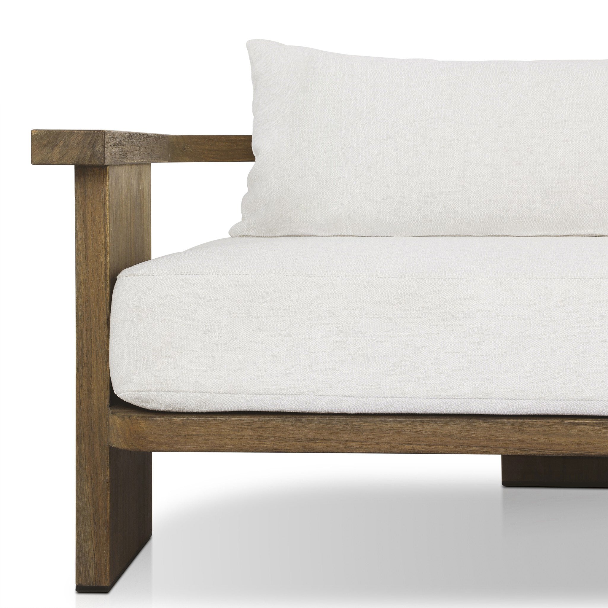 Close up of a outdoor sofa highlighting the white cushions and curved wooden frame. 
