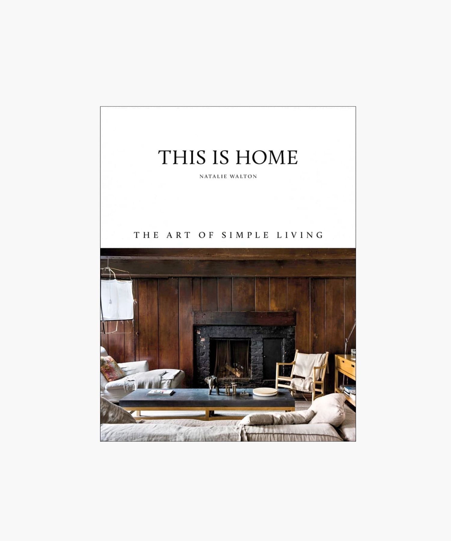 Cover of the book "This Is Home" by Natalie Walton, featuring a rustic, cozy living room with wooden walls, a fireplace, seating, and a coffee table. | S.W. Home