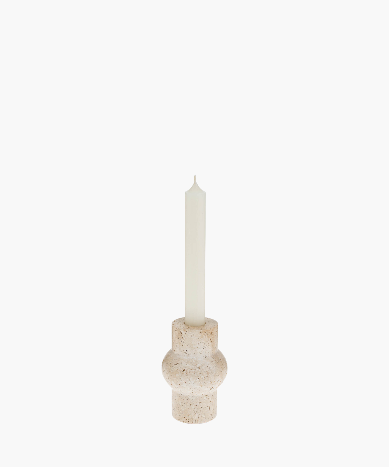 A tall white candle in a rounded, beige travertine stone holder with a textured surface. The minimalist design evokes a calm and serene atmosphere. | SW Home