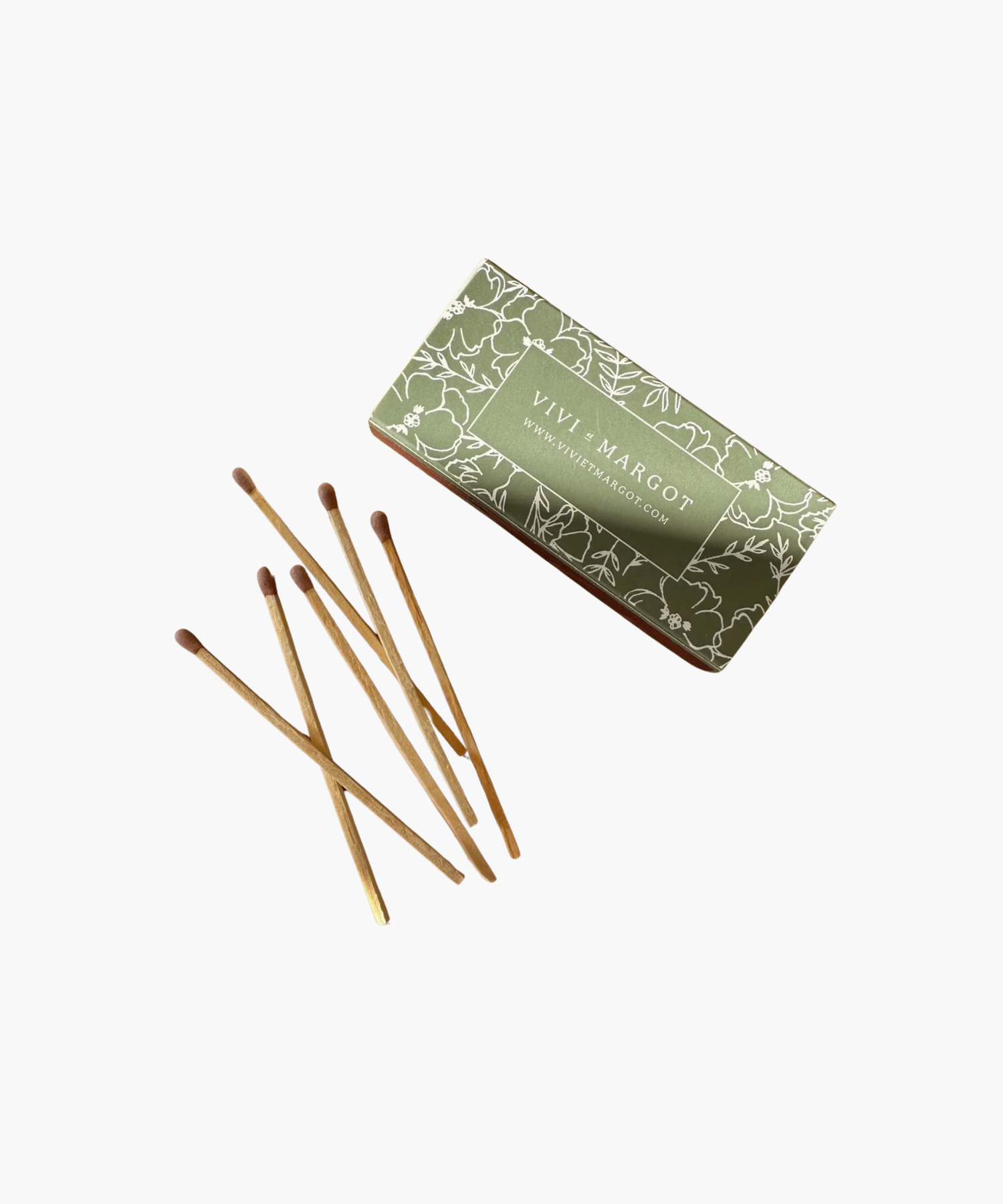 A green floral matchbox labeled "Vivi et Margot" is next to seven wooden matches with brown tips, conveying a rustic and elegant feel. | SW Home