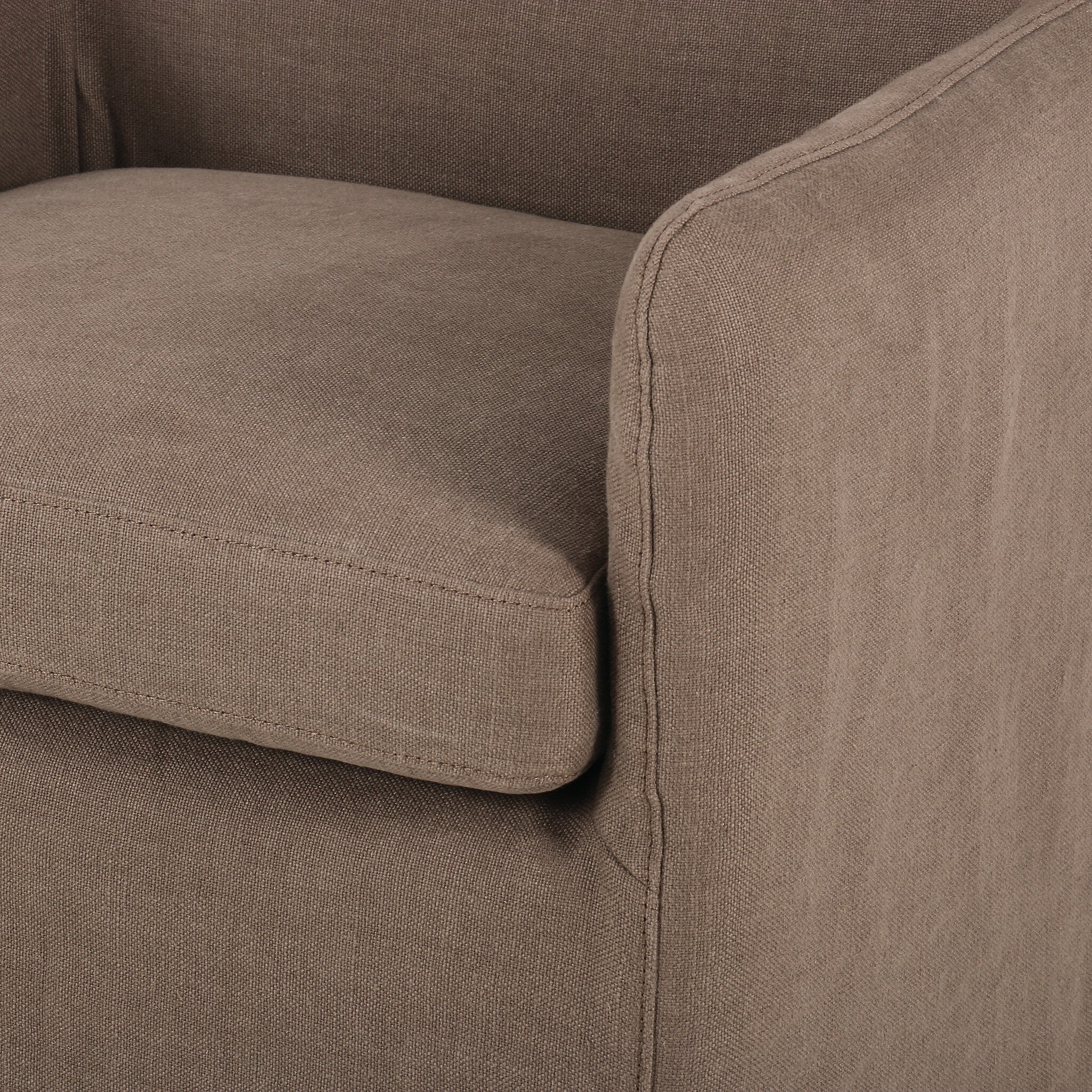 Slipcovered dining chair in an earthy mushroom brown hue with rounded arms on a white background. 