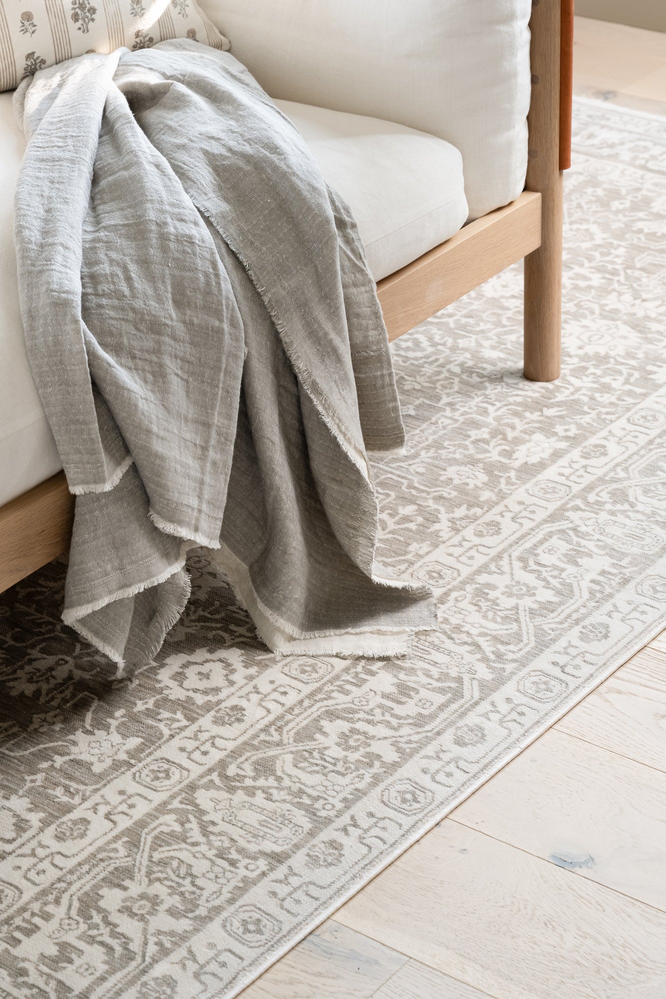 A cozy beige sofa with a soft gray throw draped over the arm sits on a patterned rug. The setting conveys a warm, inviting atmosphere.